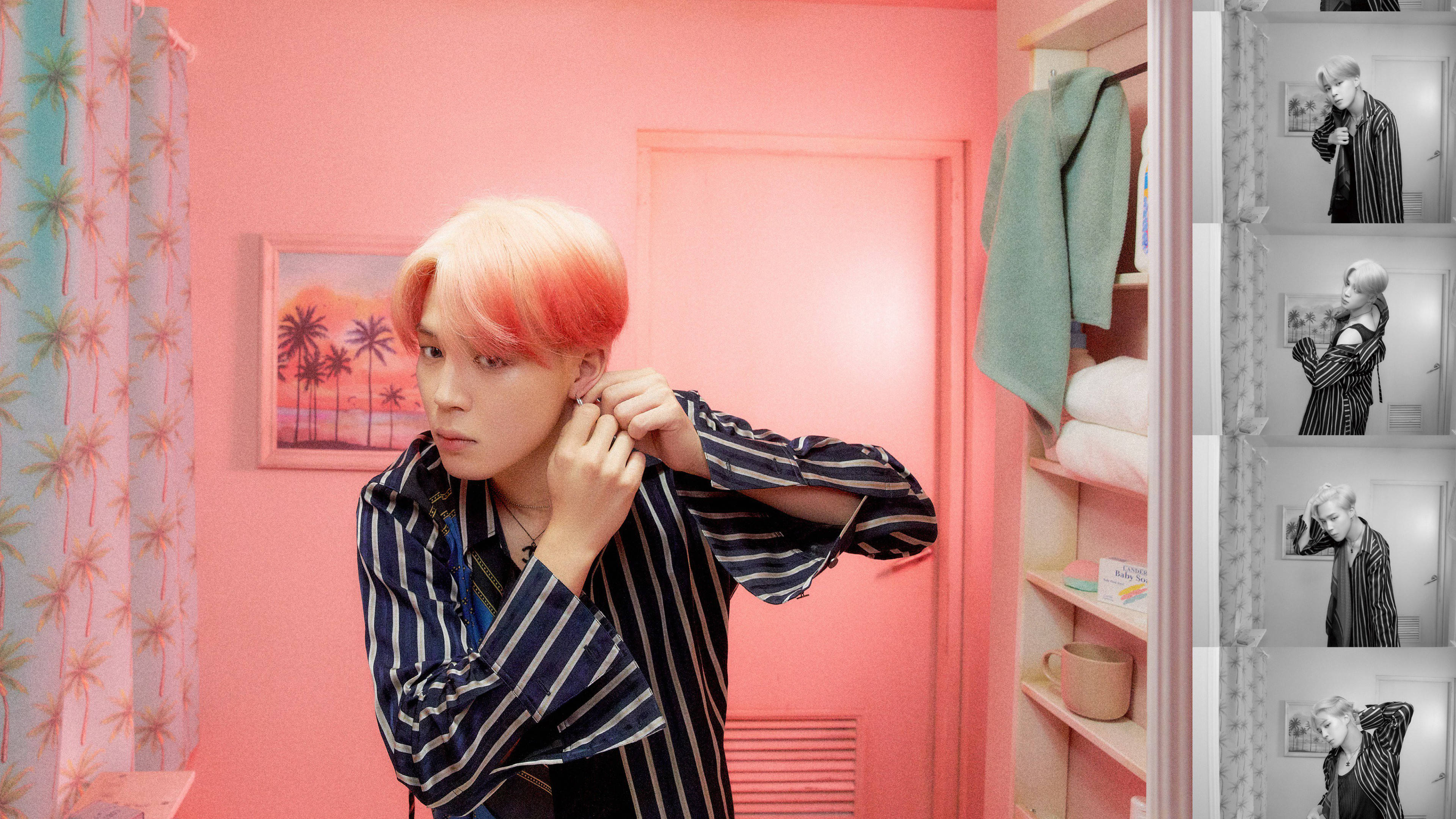 金珍洙《Map Of The Soul: Persona》版本2 鏡面照 壁紙 — 一個粉紅色頭髮的人正在一個有棕櫚樹藝術品和衣櫃的鮮豔粉紅色房間裡調整耳環。