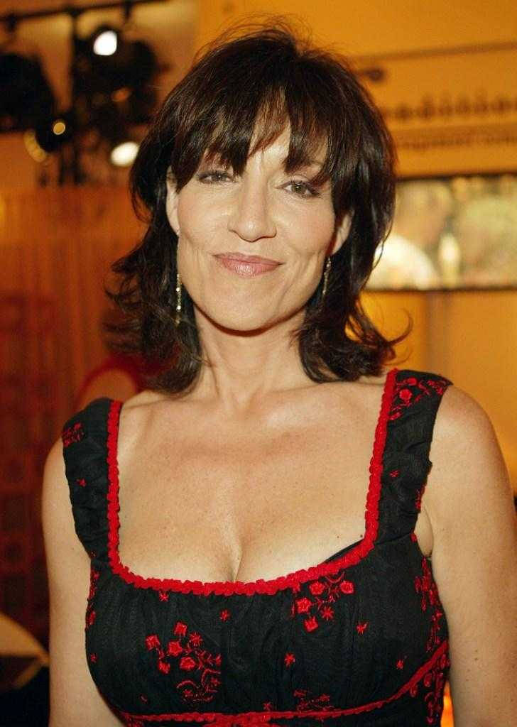 穿著帶有紅色刺繡的黑色連衣裙的女性在溫暖燈光下於室內微笑。