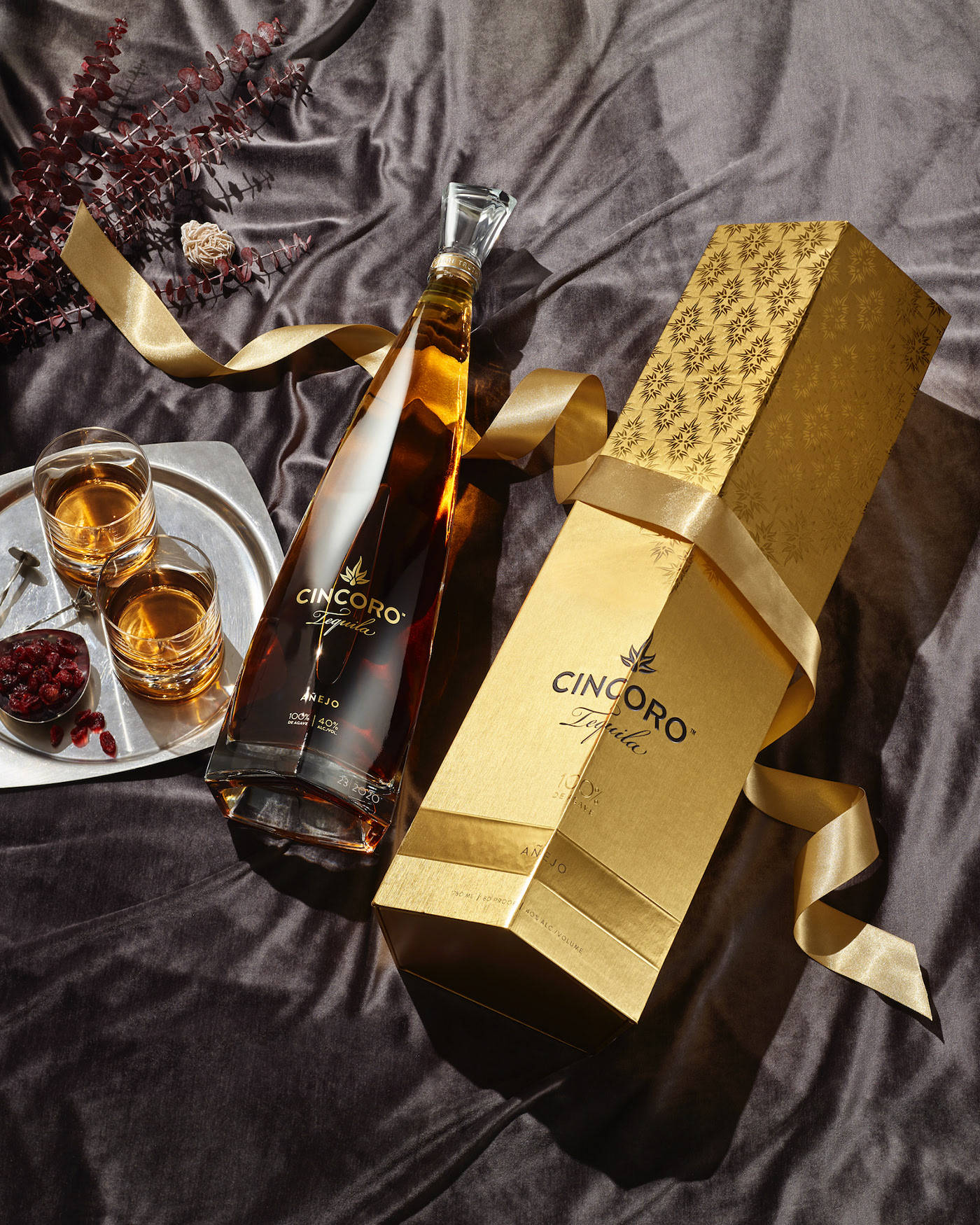 Cincoro龍舌蘭酒瓶和禮盒，附品酒杯，置於深色緞面上。