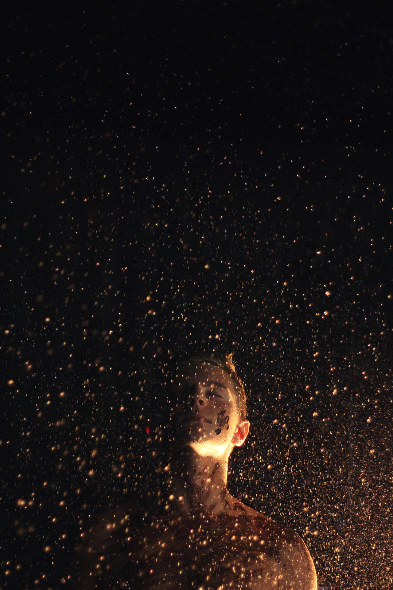 在黑暗背景下，被墜落的金色火花包圍的人。