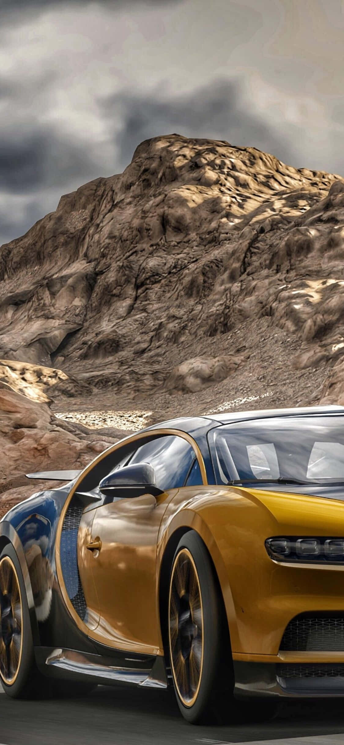金色 Bugatti Chiron 飛越巨石 iPhone X Forza Motorsport 7 背景 壁紙 — 一輛金色Bugatti Chiron在暴風雨的天空下，以崎嶇山脈為背景，在沙漠公路上疾馳。