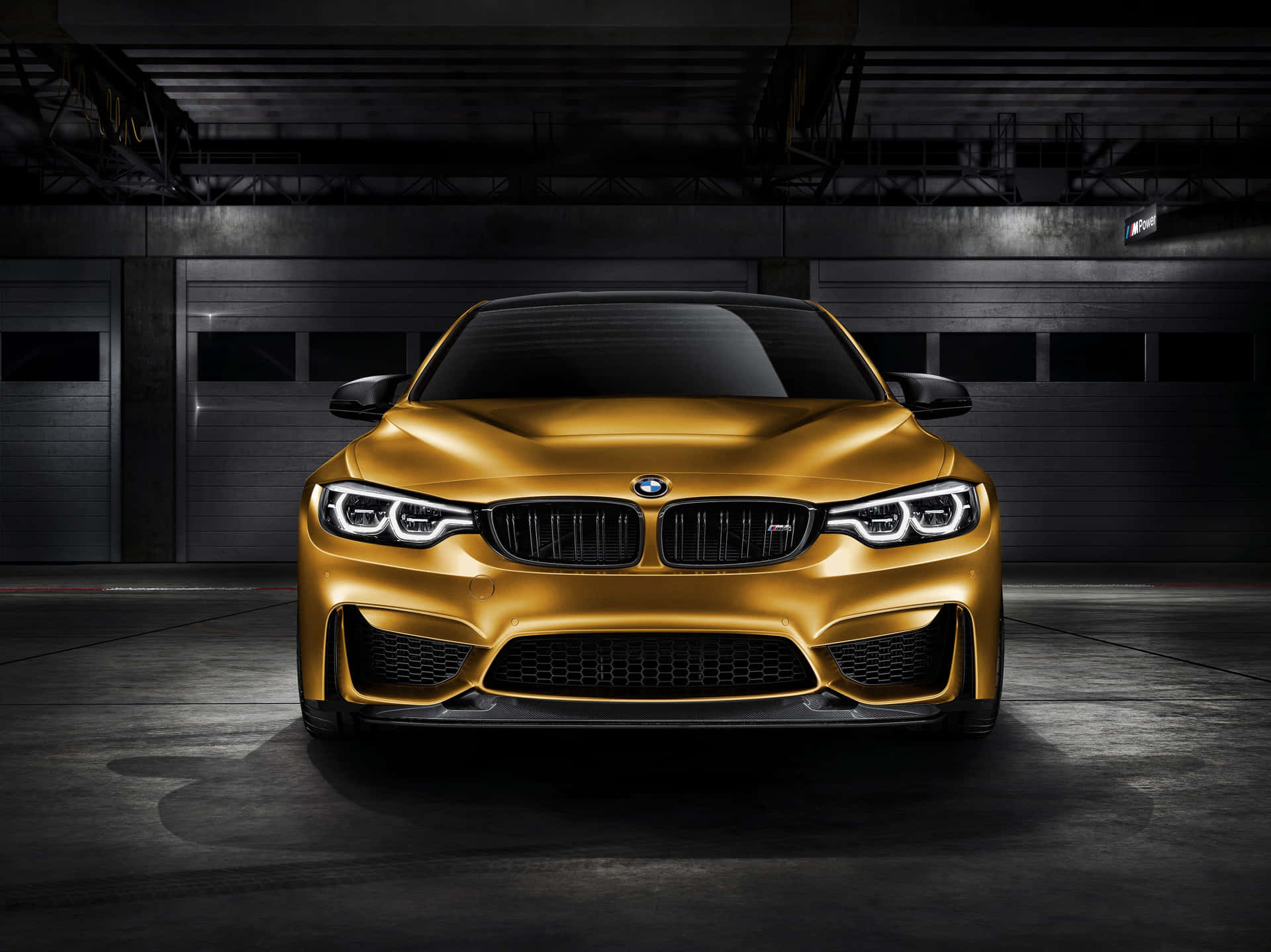昏暗工業車庫中的金色BMW M4跑車。