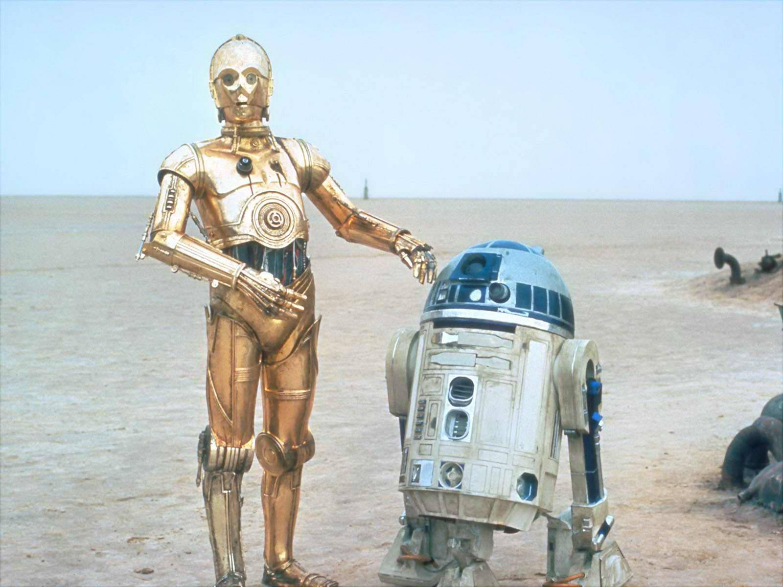 Droid 桌布 壁紙 — 金色C3PO和凹陷的R2D2並肩站在廣闊的沙漠中，天空蒼白。