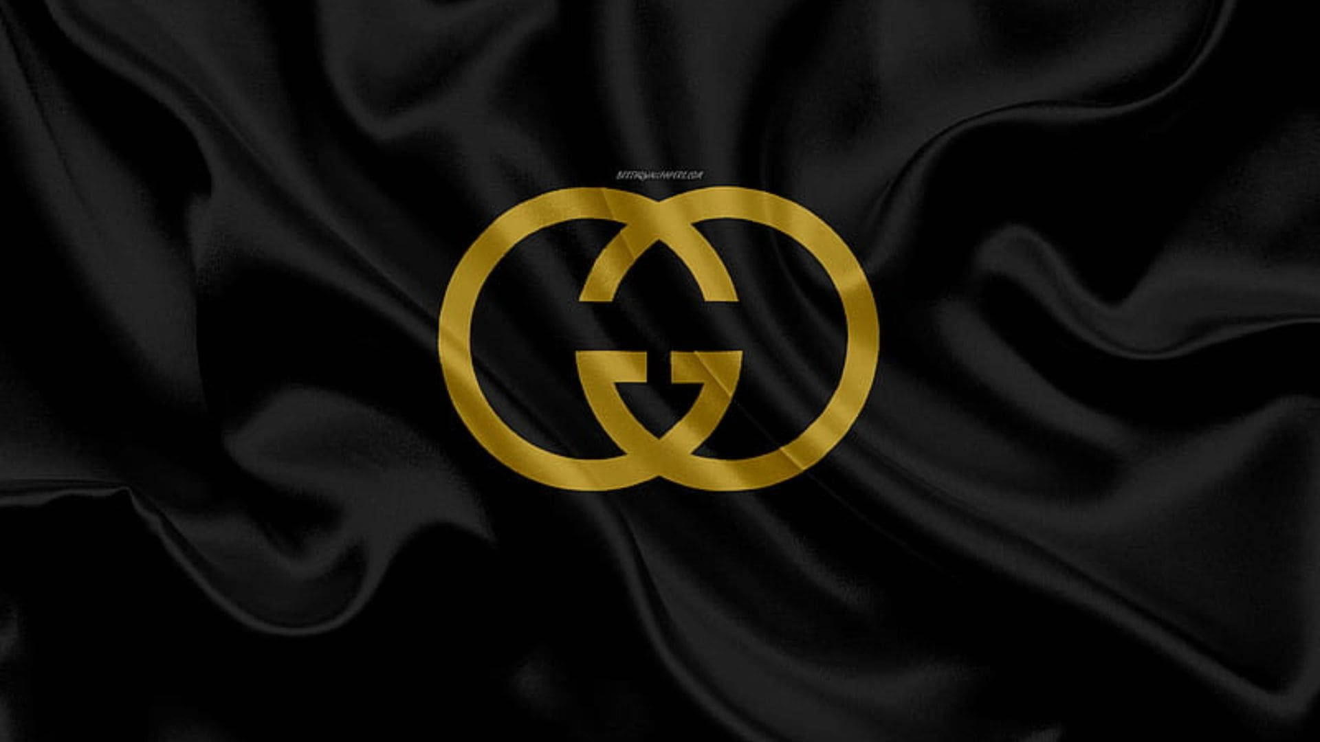 Gucci 桌布 壁紙 — 金色Gucci標誌在奢華的黑色緞面布料上閃耀，帶有深邃的褶皺和柔和的高光。
