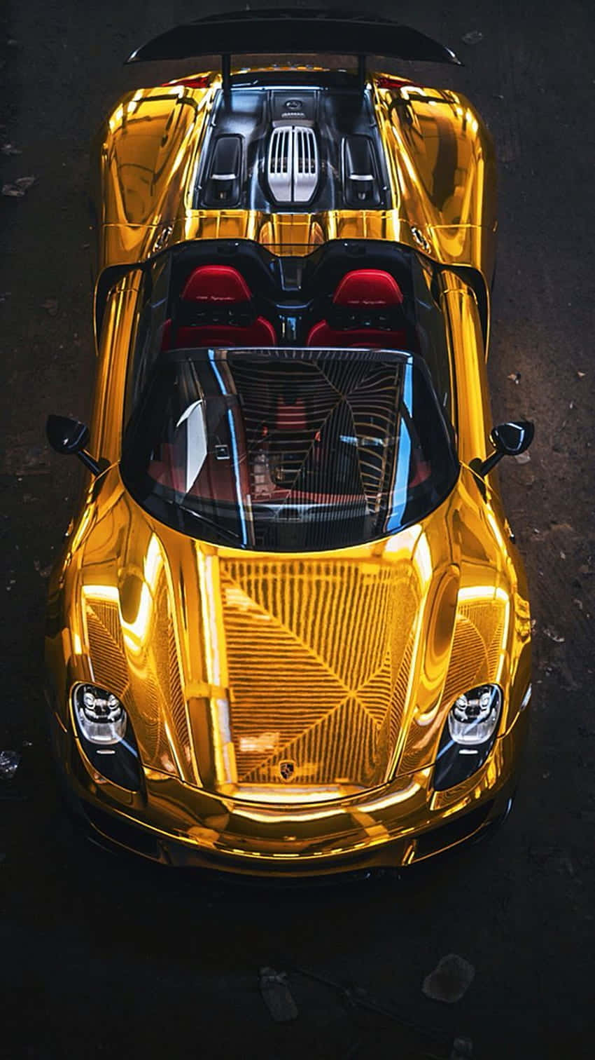 金色保時捷透明後視 壁紙 — 從上方俯瞰一輛閃閃發光的金色跑車，配備紅色座椅，停泊在深色瀝青路面上。