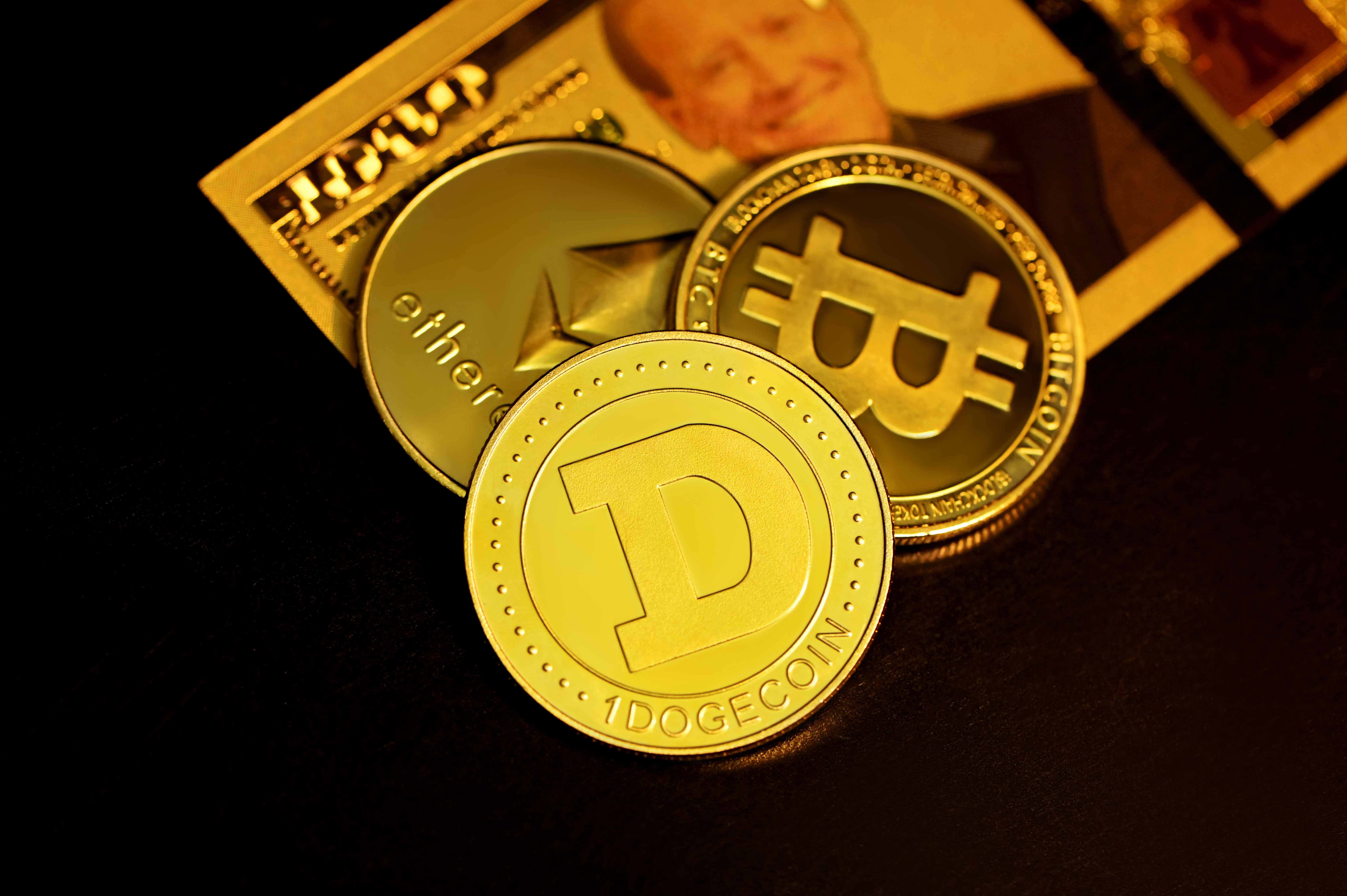 Dogecoin 桌布 壁紙 — 金色加密貨幣硬幣，包括狗狗幣、比特幣和以太幣，在溫暖的燈光下放在一張美元鈔票上。