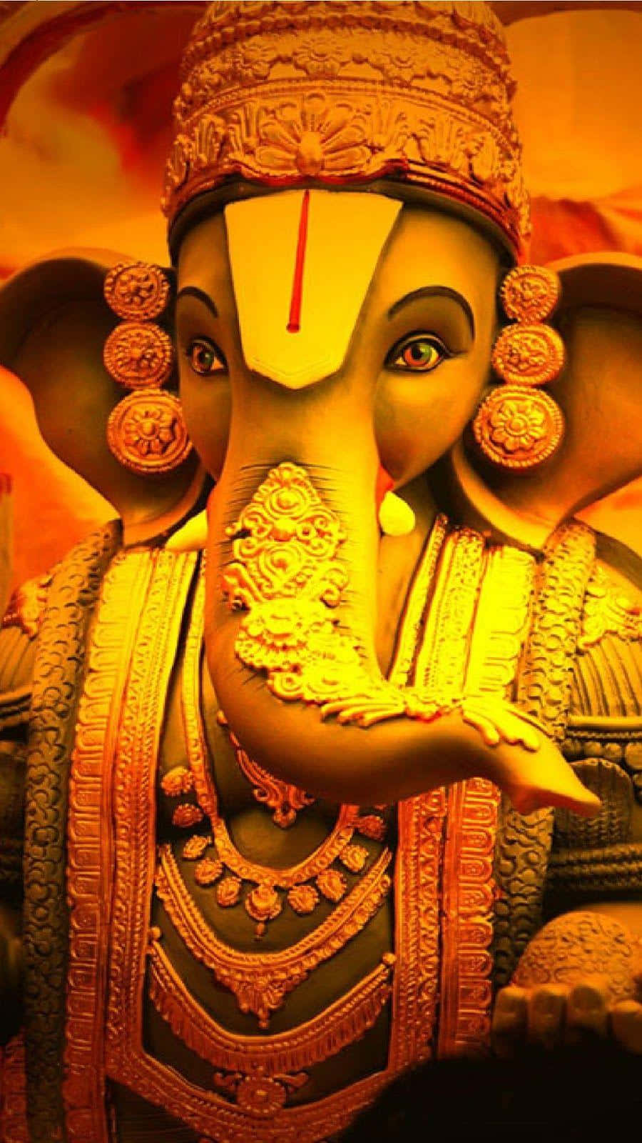 金色印度神祇 Ganpati Bappa 圖像 壁紙 — 一尊閃耀的黃金象頭神像，飾以精緻珠寶和皇冠，在熾熱的橙色背景下溫暖發光。