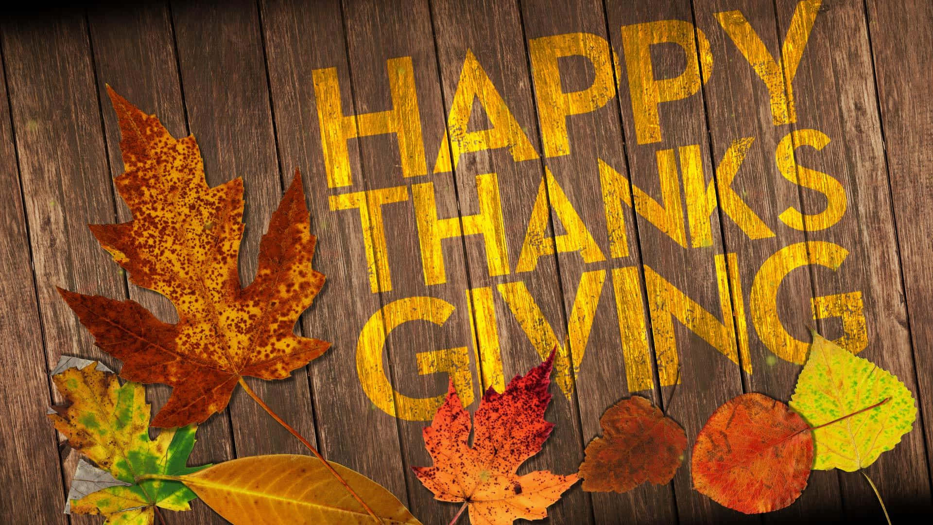 Happy Thanksgiving 桌布 壁紙 — 金色嘅「HAPPY THANKSGIVING」字樣畫喺風化嘅木頭上，周圍係鮮豔嘅秋葉。