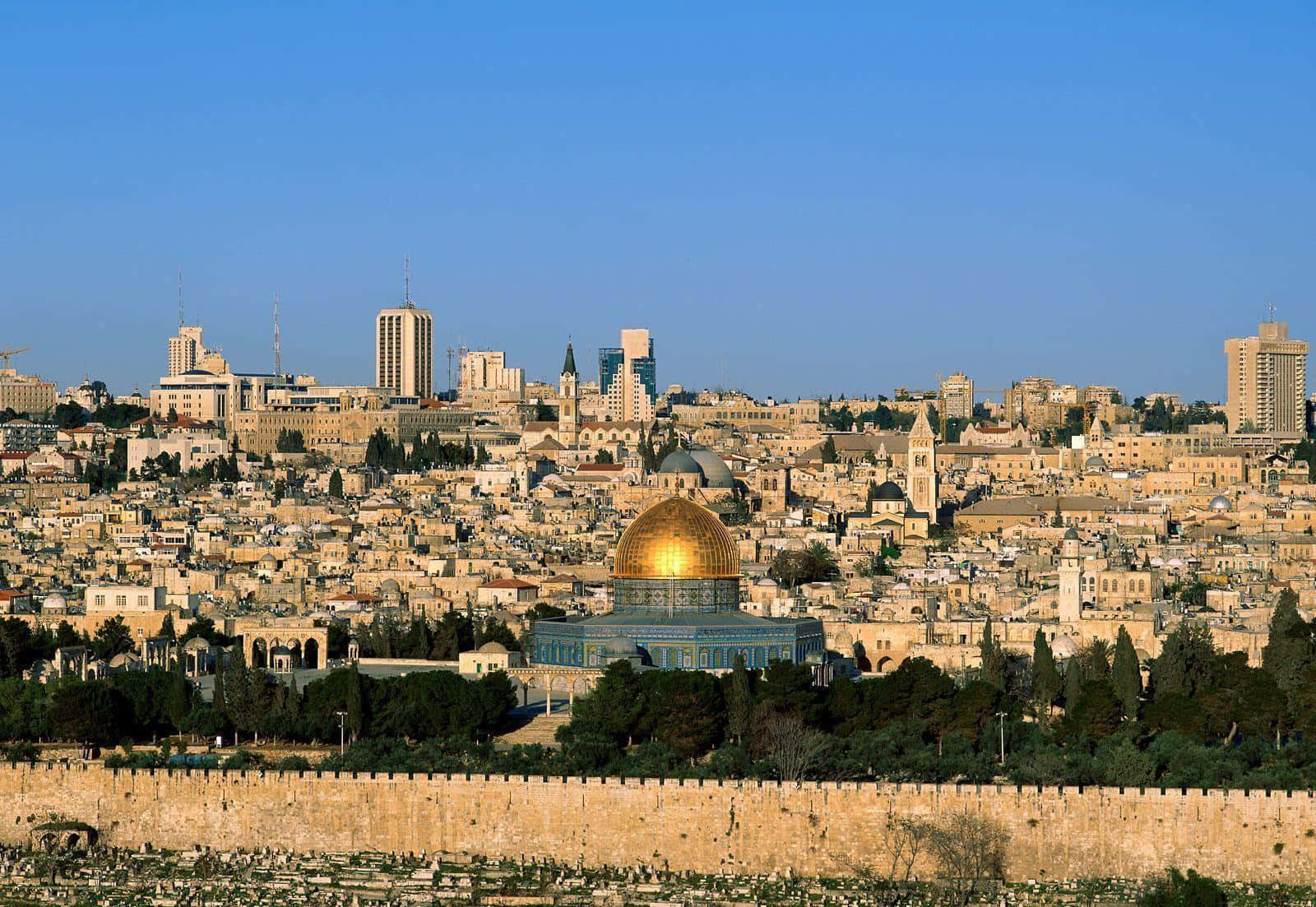 Israel 桌布 壁紙 — 金色圓頂清真寺在清澈藍天下閃耀，下方是古老的石頭城市景觀，遠處有現代建築。