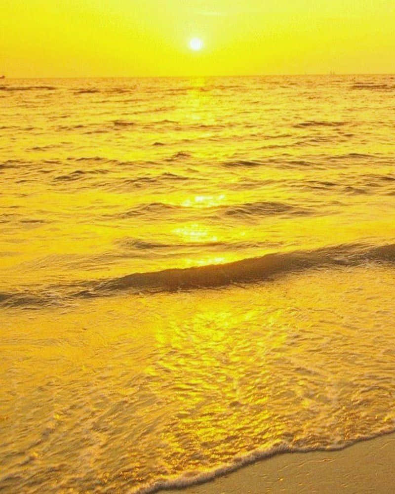 Yellow Beach 桌布 壁紙 — 金色夕陽以溫暖的光芒沐浴著海浪，輕輕拍打著沙灘。