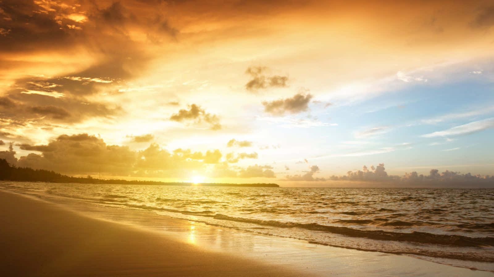 Yellow Beach 桌布 壁紙 — 金色夕陽以溫暖色調塗抹天空和海洋，海浪在戲劇性的雲層下輕輕拍打沙灘。