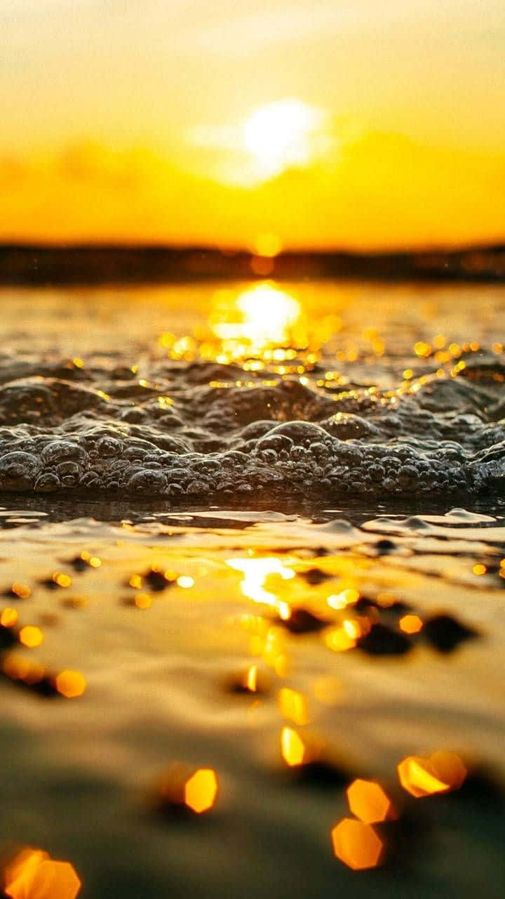 Yellow Sunset 桌布 壁紙 — 金色夕陽在泡沫海浪上閃爍，淺水中呈現六角形散景反射。