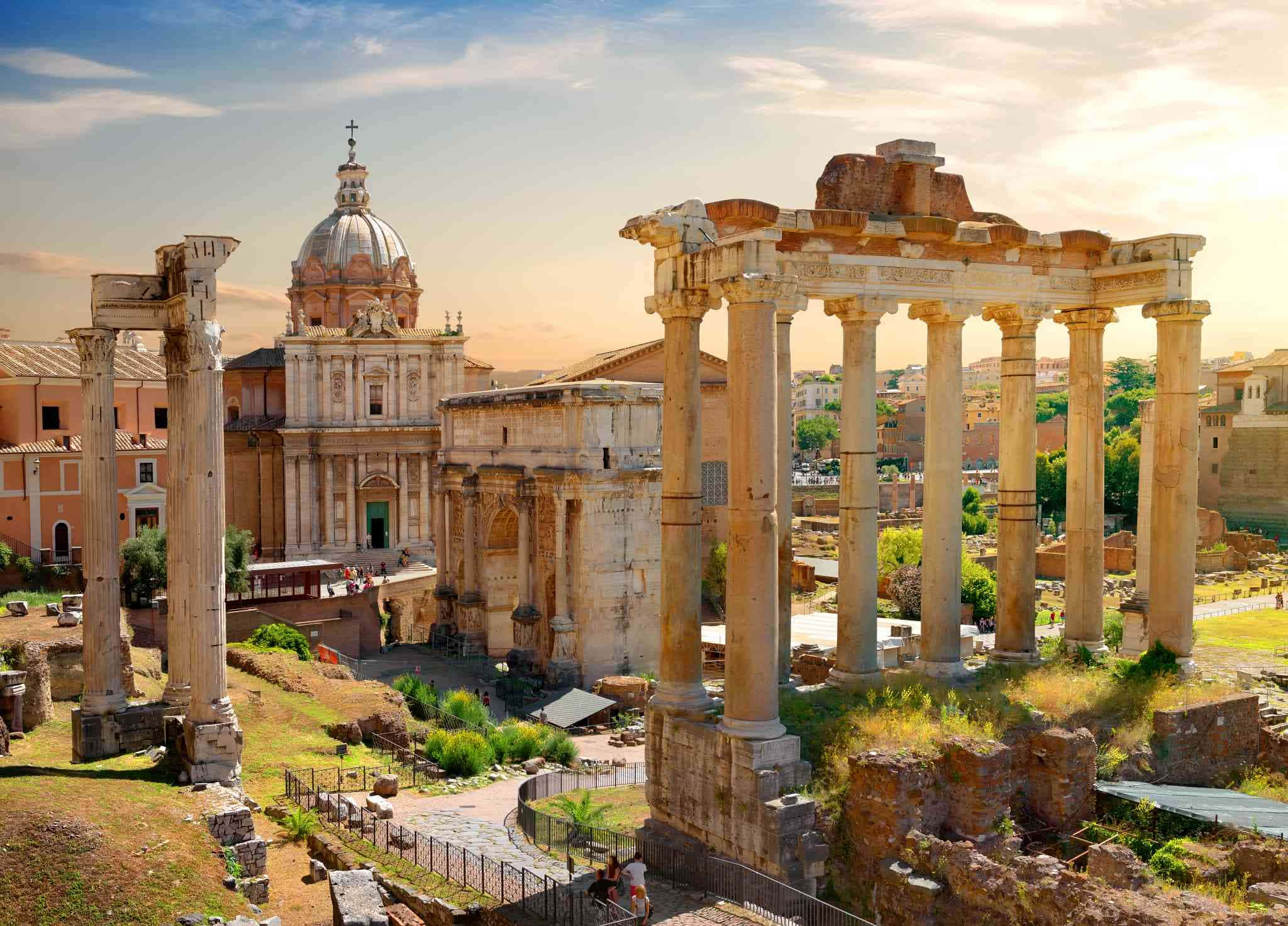 Roman 桌布 壁紙 — 金色夕陽天空下的古羅馬遺跡，有高聳的柱子和圓頂教堂。