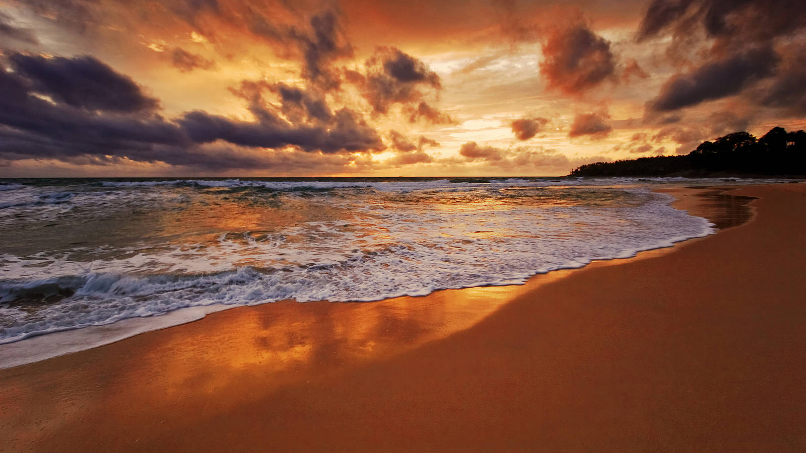 Beach Desktop 桌布 壁紙 — 金色夕陽海浪拍打溫暖沙灘，天空佈滿戲劇性的橙色和紫色雲彩。