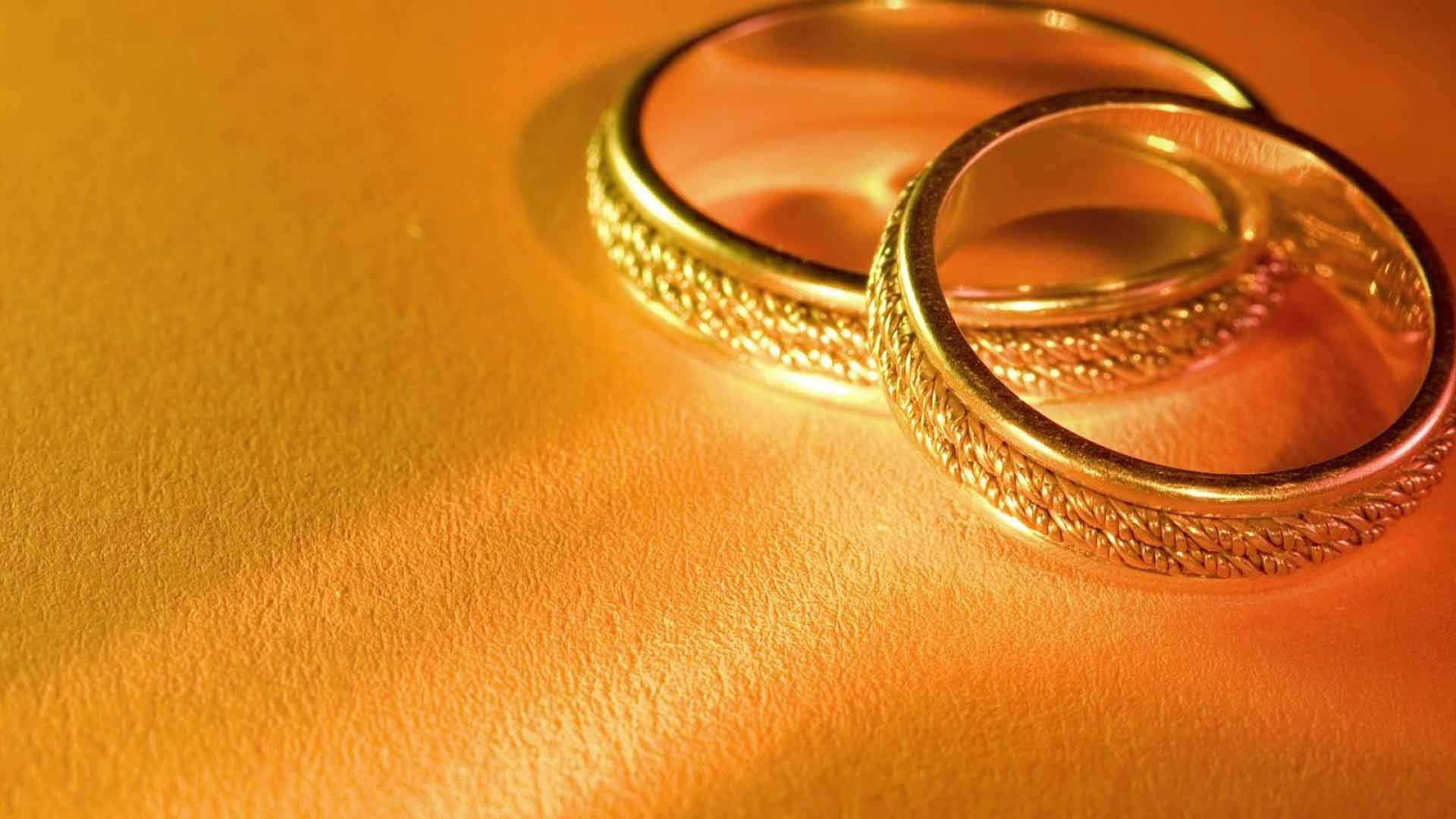 兩枚金色結婚戒指一起放在帶紋理的金色表面上。