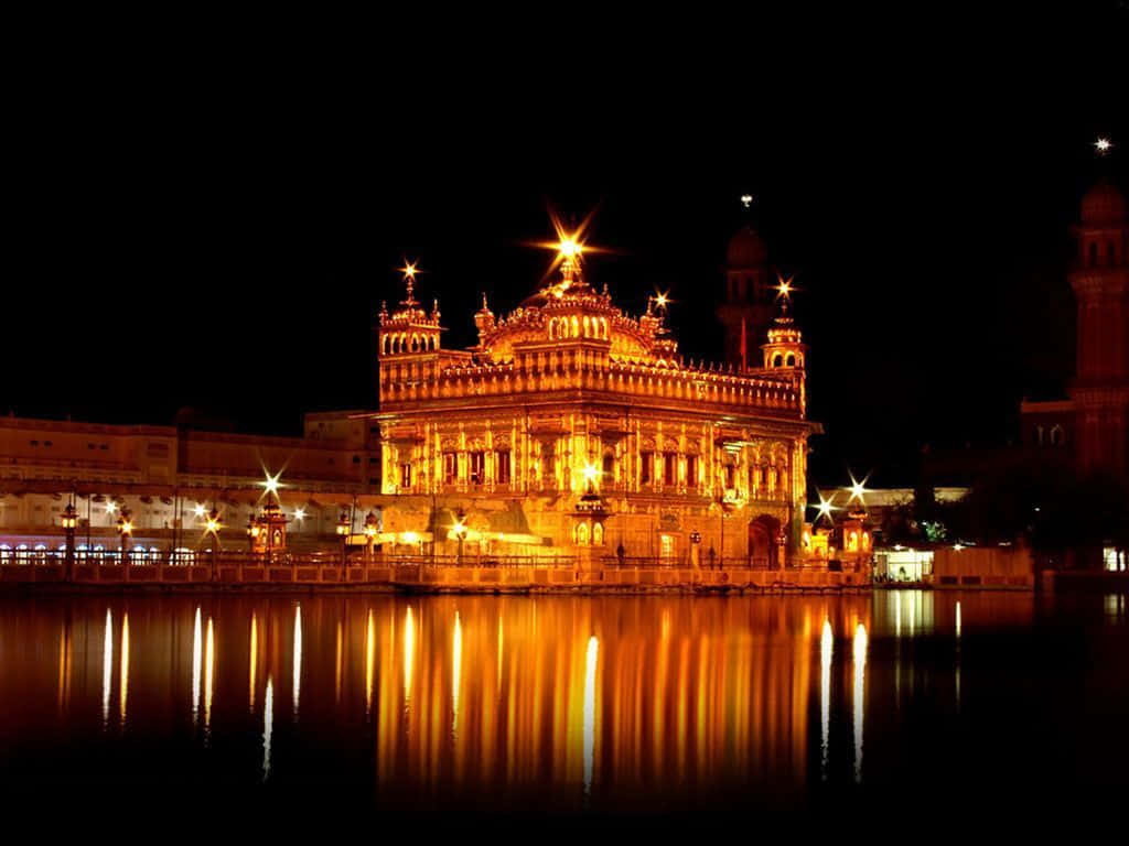 Golden Temple 桌布 壁紙 — 金色寺廟在夜晚被溫暖的燈光照亮，在平靜的水面上美麗地倒映。