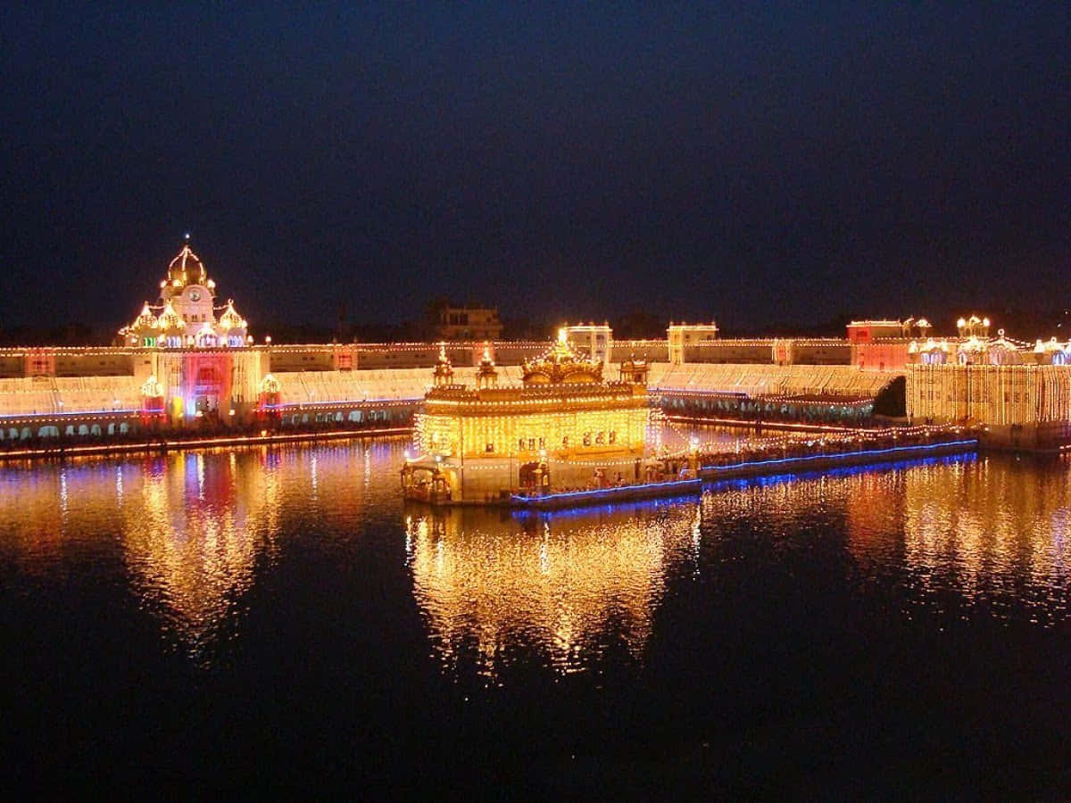 Golden Temple 桌布 壁紙 — 金色寺廟在夜晚被照亮，鮮豔燈光在黑暗天空下平靜的水面上反射。