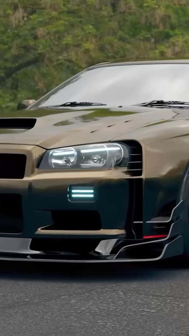 金色日產GT-R帶藍色燈光，停在靠近綠樹的道路上。