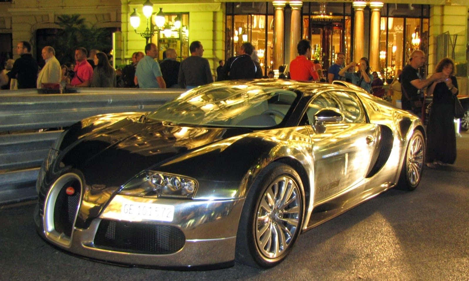 夜間停泊的銀色Bugatti Veyron，屏障後方有群眾。