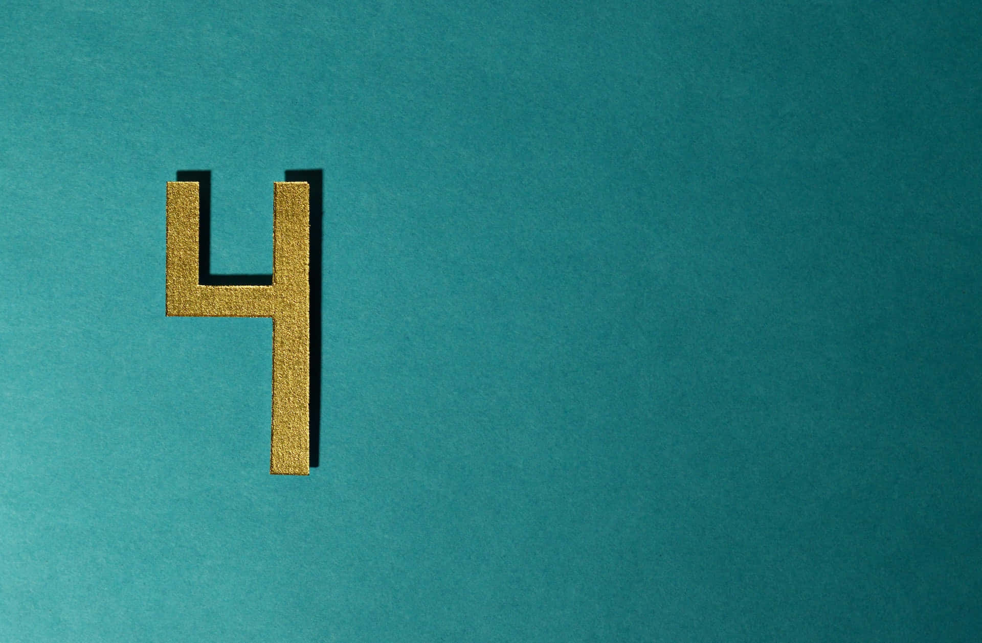 金色數字4對比藍色背景圖 壁紙 — 一個帶紋理的金色數字四，在純青色背景上帶有柔和陰影，大膽地矗立。