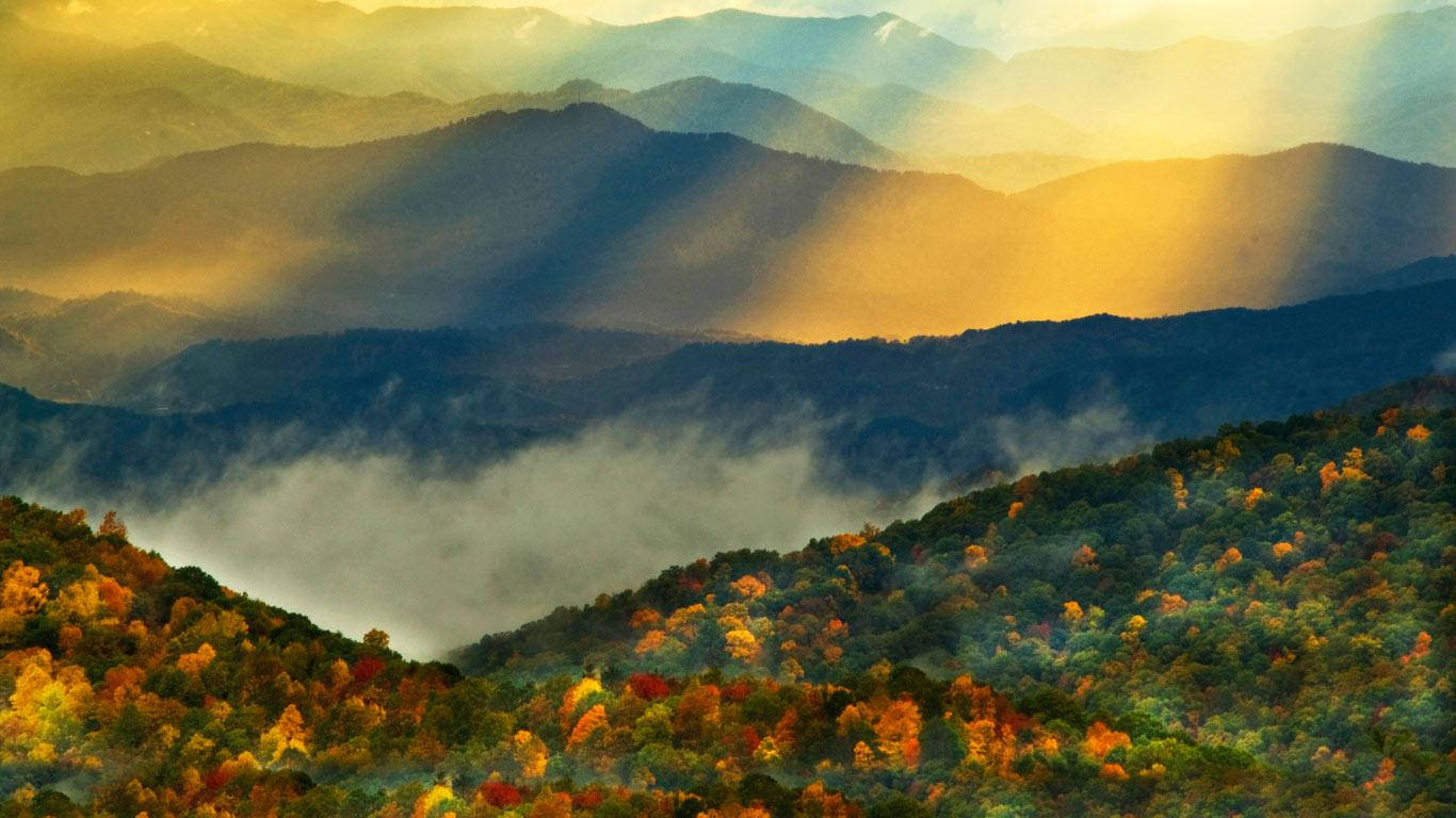 陽光穿過薄霧，照耀在色彩繽紛的秋山上。