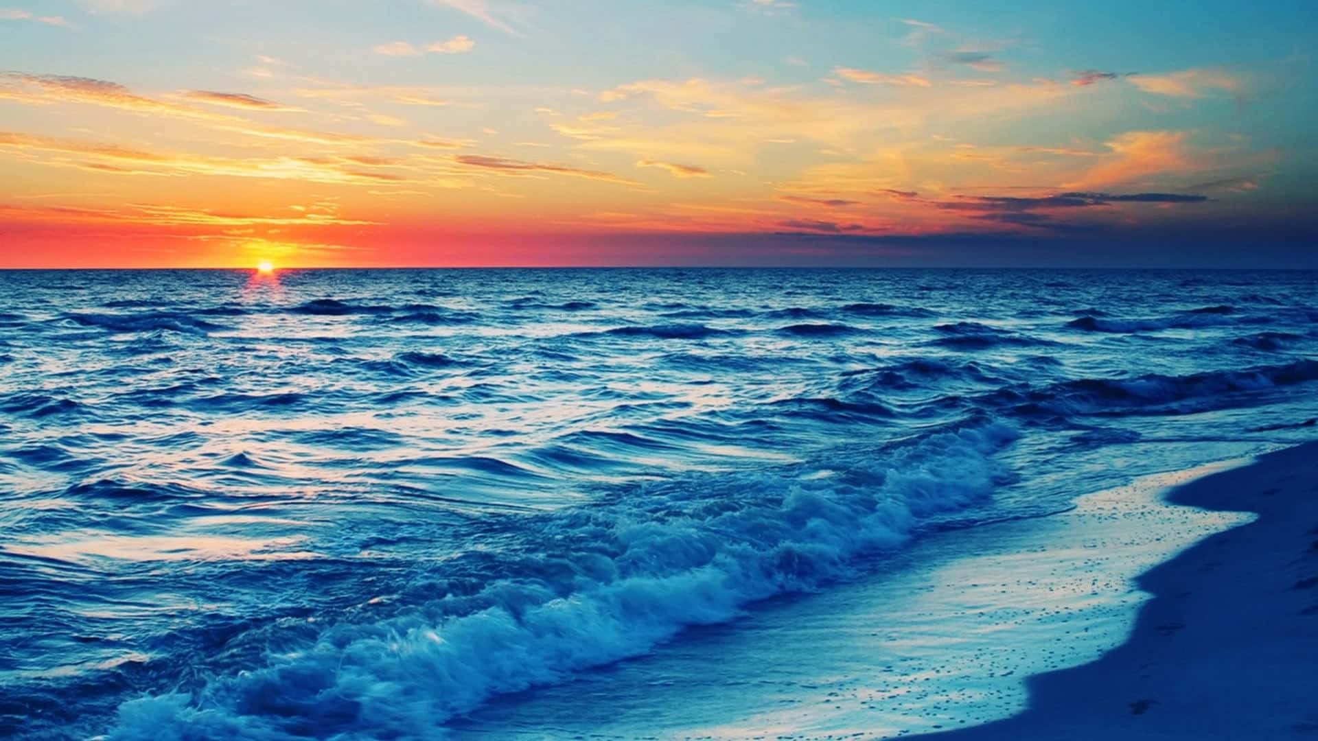 金色日落灑滿寧靜海灘 壁紙 — 夕陽將天空染成火熱的橙色和粉紅色，海浪在黃昏時拍打著沙灘。
