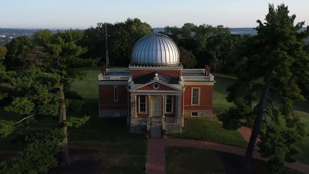 Observatory 桌布 壁紙 — 金色時刻，一座紅磚天文台帶銀色圓頂，坐落在茂密綠樹之間的鳥瞰圖。