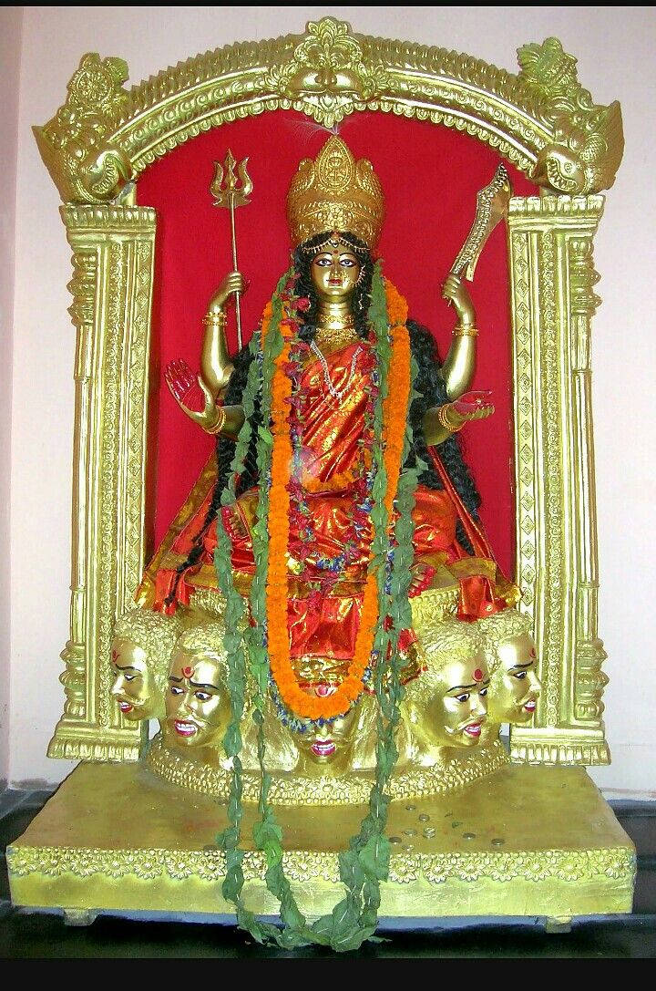 Goddess 桌布 壁紙 — 金色杜爾迦女神雕像，有多臂和多頭，飾有紅色和橙色花環，背景為紅色。
