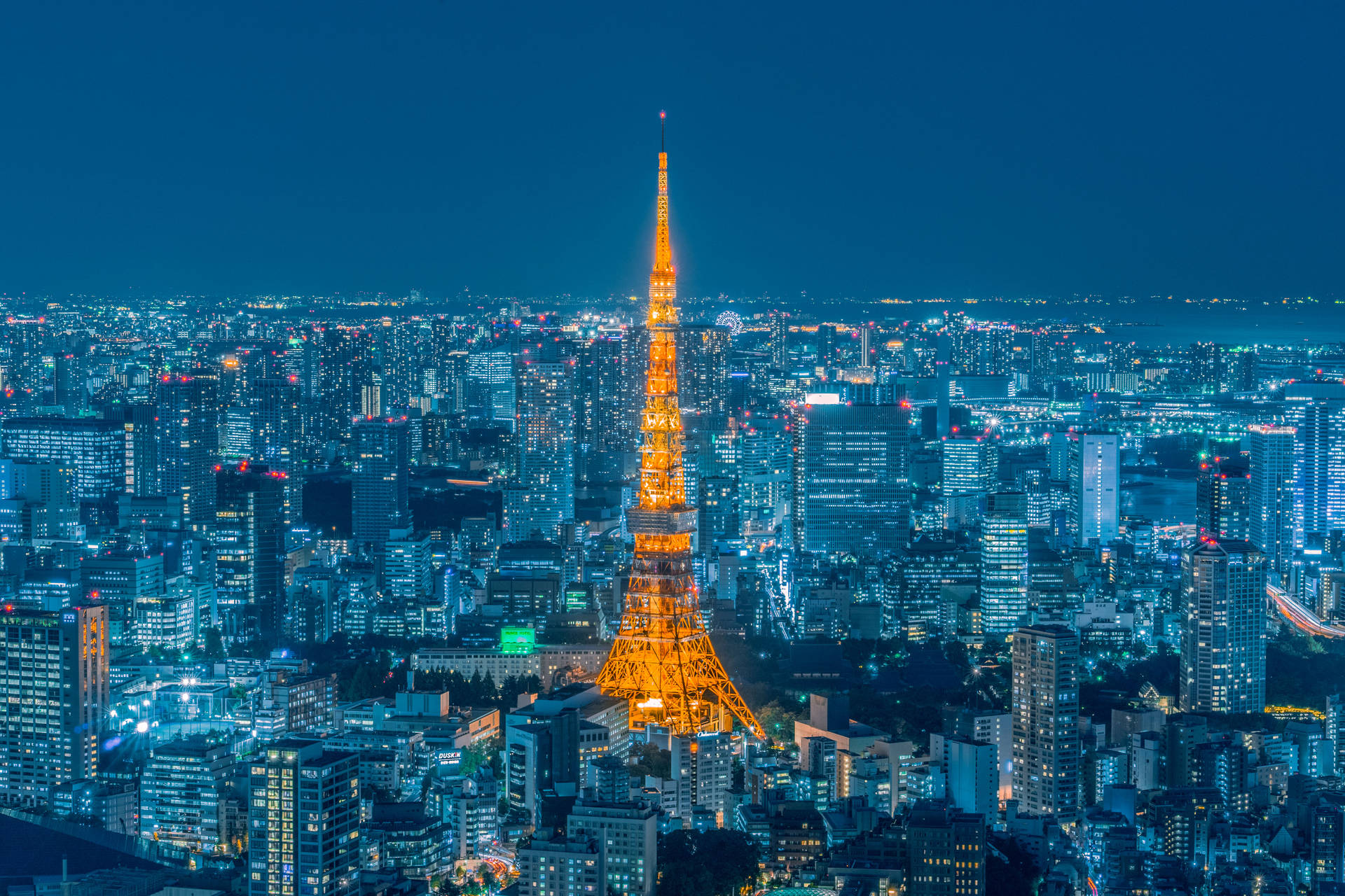 金色東京鐵塔對比黃昏天際 壁紙 — 東京塔在深藍色夜空下溫暖地發光，下方是廣闊的閃爍城市景觀。