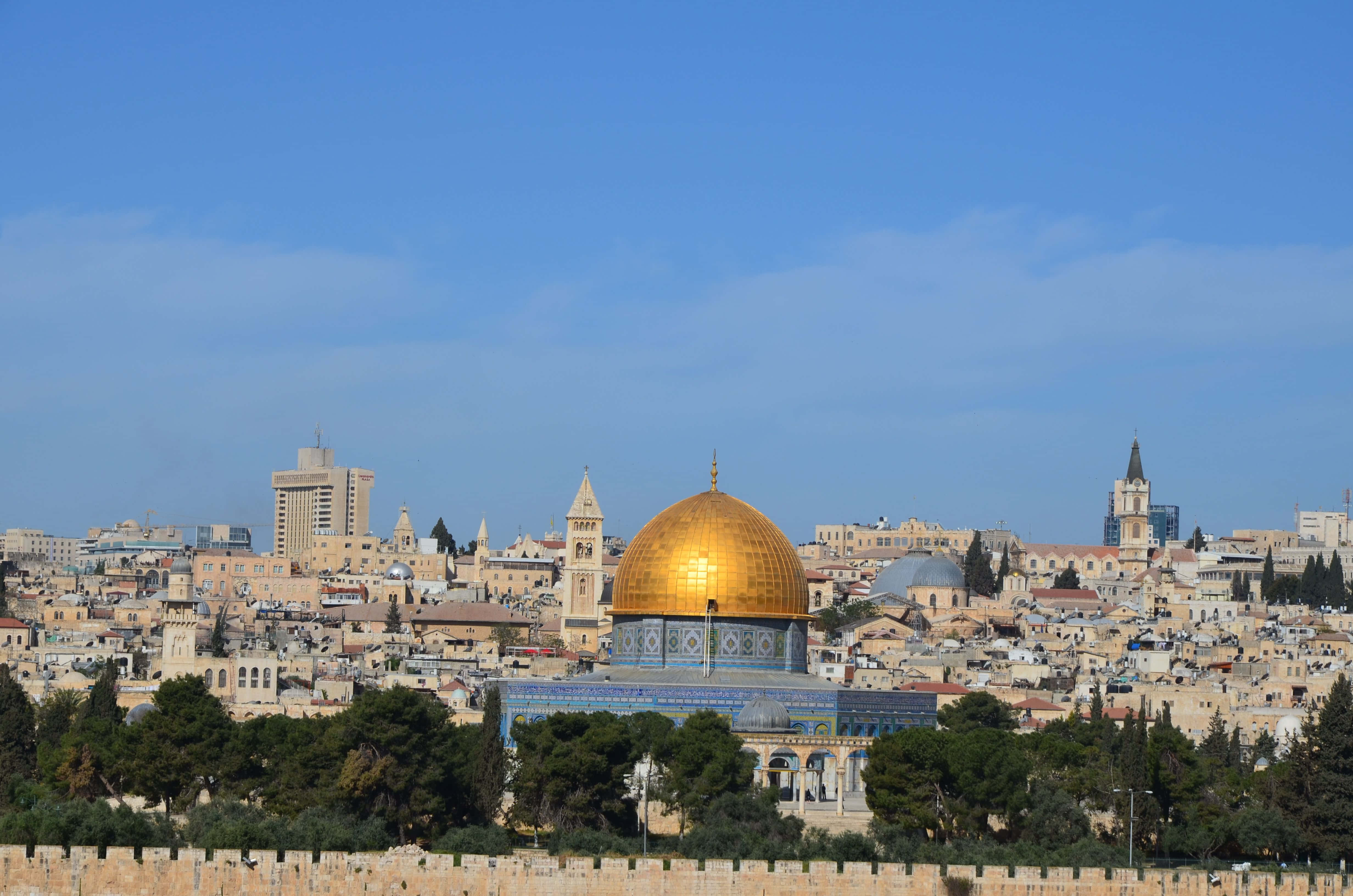 Holy Land 桌布 壁紙 — 金色的圓頂清真寺在耶路撒冷古老石建築和綠樹上方的清澈藍天下閃耀。