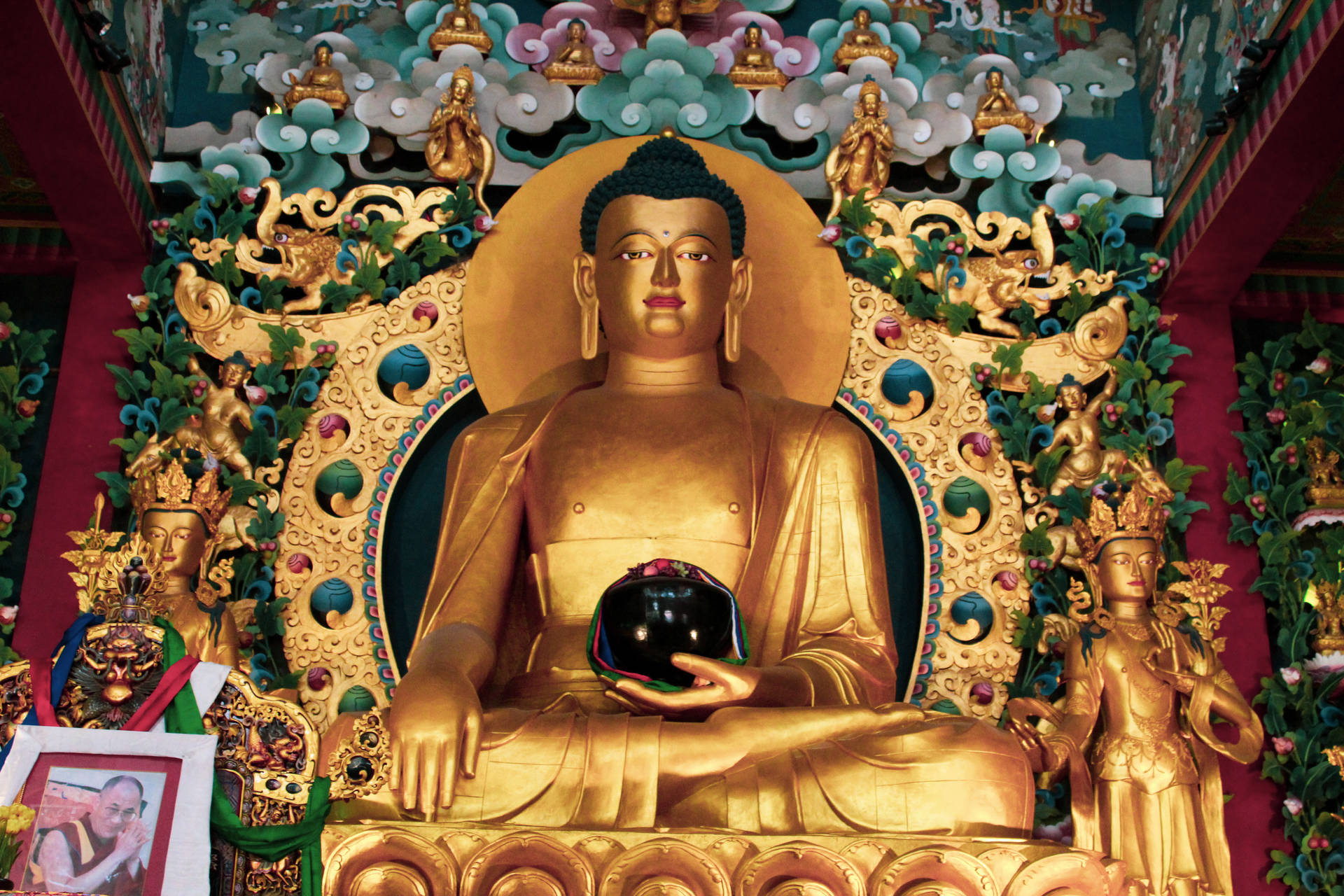 金色佛像在裝飾著神祇和花朵的寺廟中手持黑色球體。