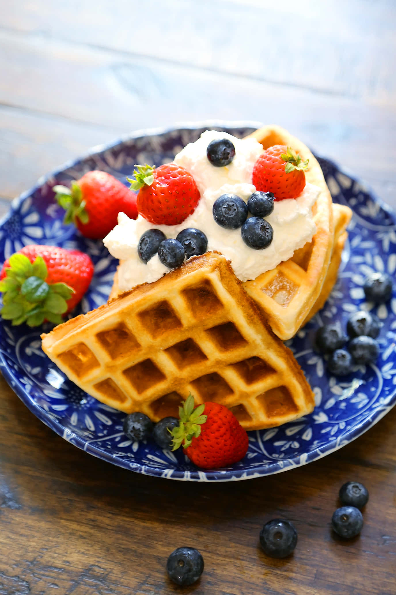 Waffle 桌布 壁紙 — 金色窩夫配上忌廉、草莓和藍莓，放在藍色圖案碟上。