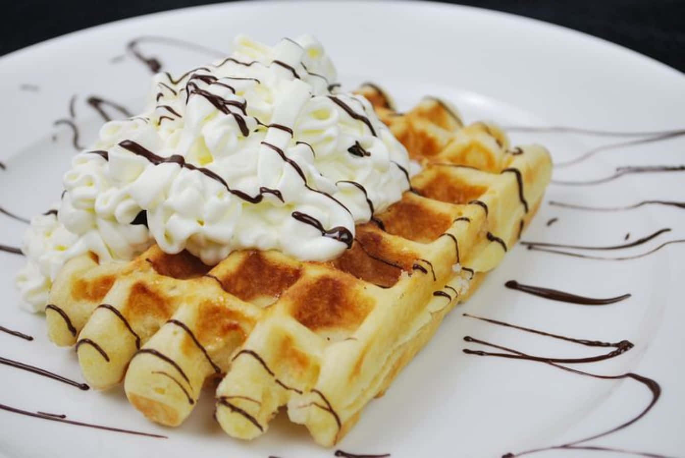 Waffle 桌布 壁紙 — 金色窩夫配上忌廉和朱古力醬，放在白色碟上。