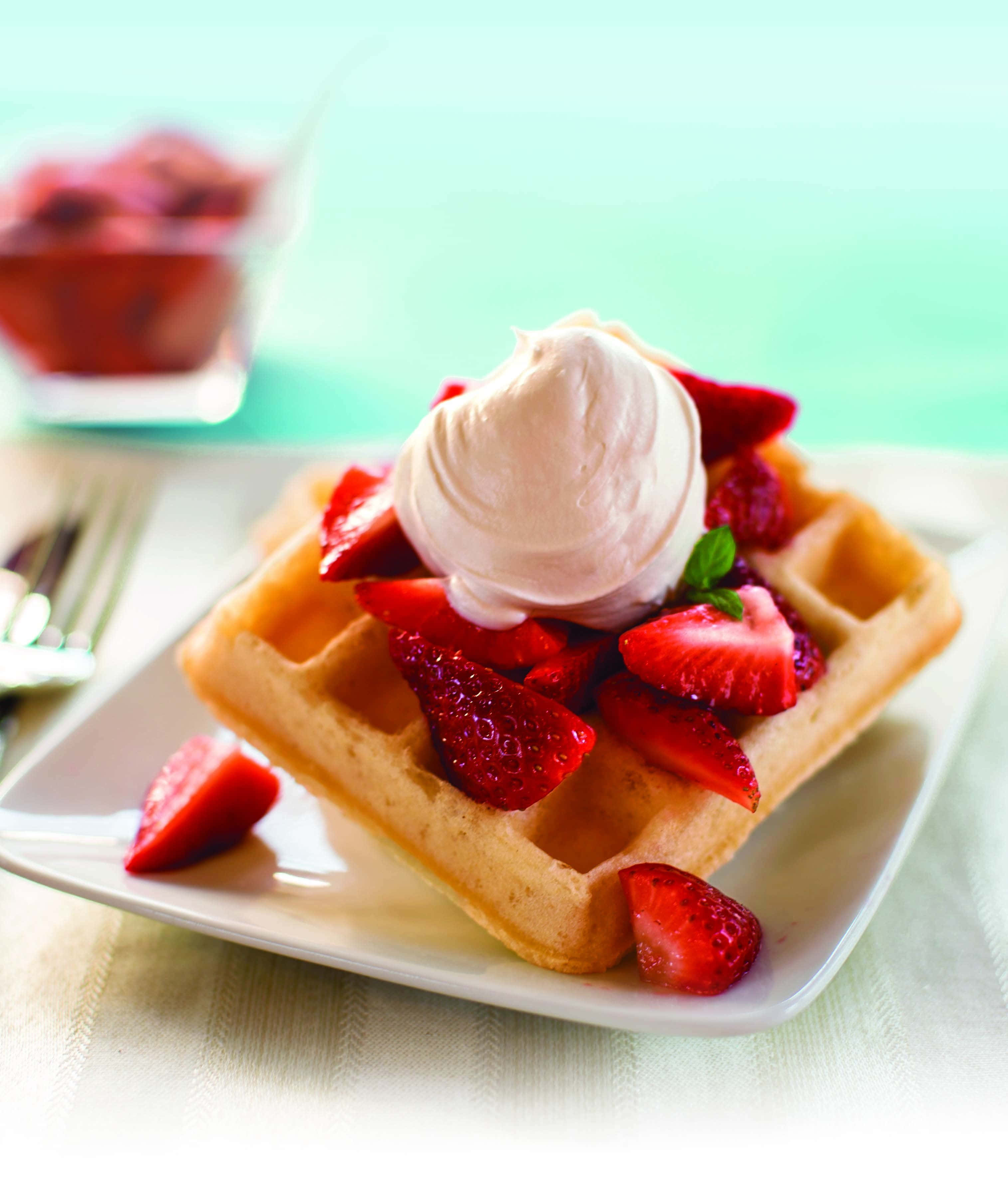 Waffle 桌布 壁紙 — 金色窩夫配上新鮮草莓、忌廉和薄荷，放在白色碟上，以柔和青綠色背景襯托。