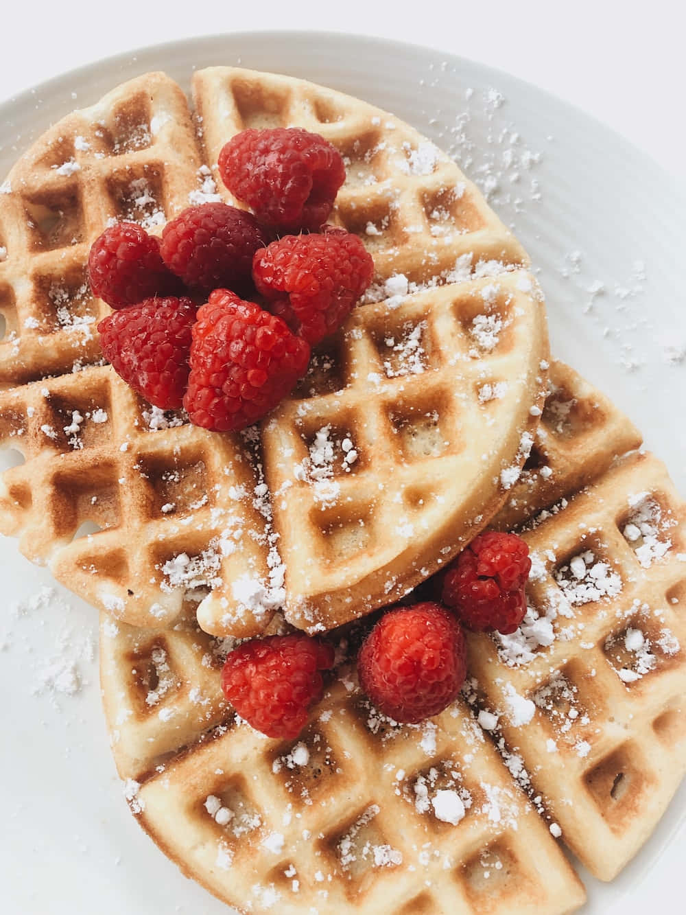 Waffle 桌布 壁紙 — 金色窩夫配上新鮮覆盆子和糖粉，放在白色碟上。
