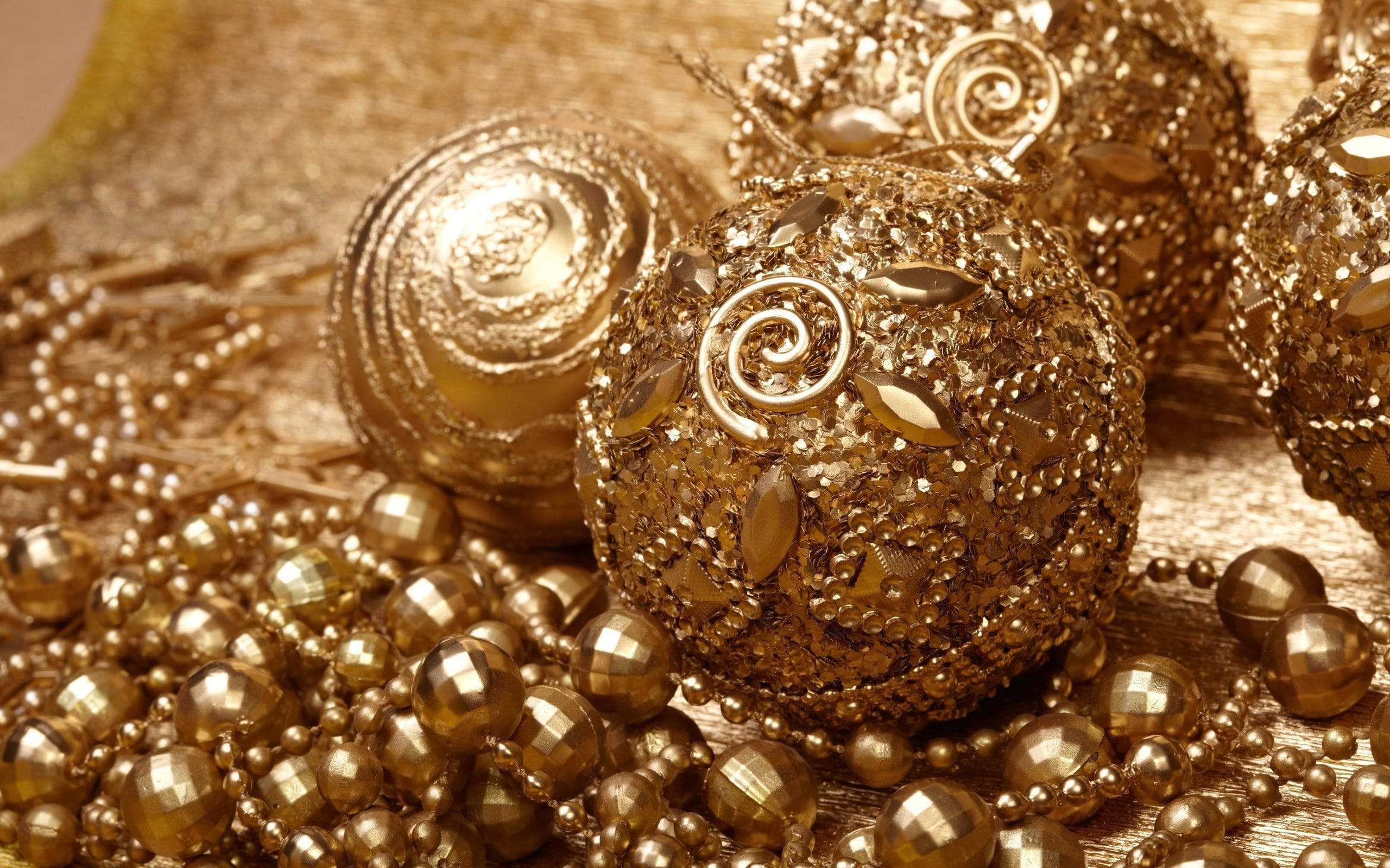 金色聖誕球裝飾 壁紙 — 金色裝飾品和珠子在紋理金表面上閃爍著複雜的漩渦和閃閃發光的刻面。