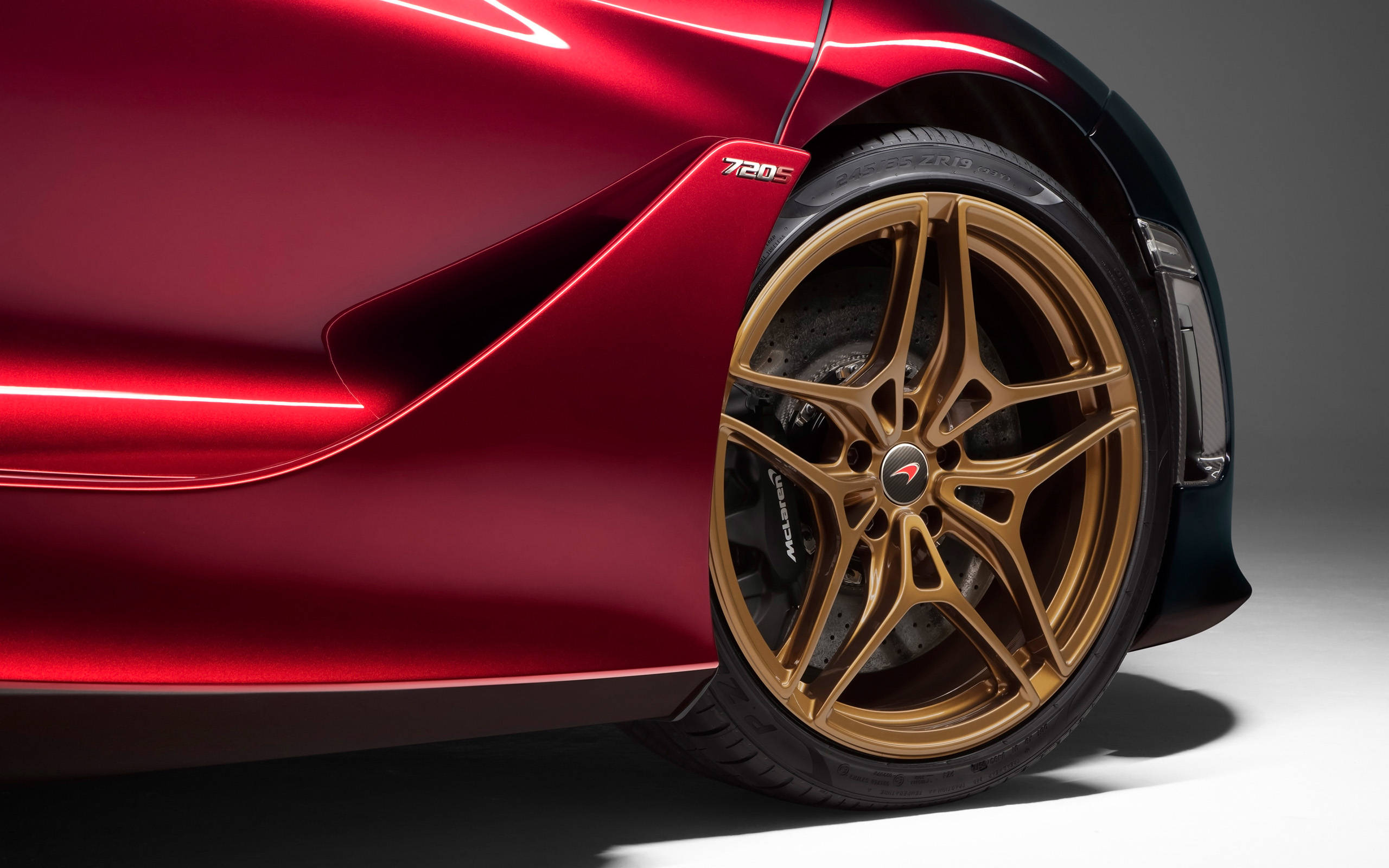 金色輪圈的麥拉倫720S 壁紙 — 紅色光面McLaren 720S跑車的特寫，突出其金色合金輪圈和空氣動力學側面輪廓。