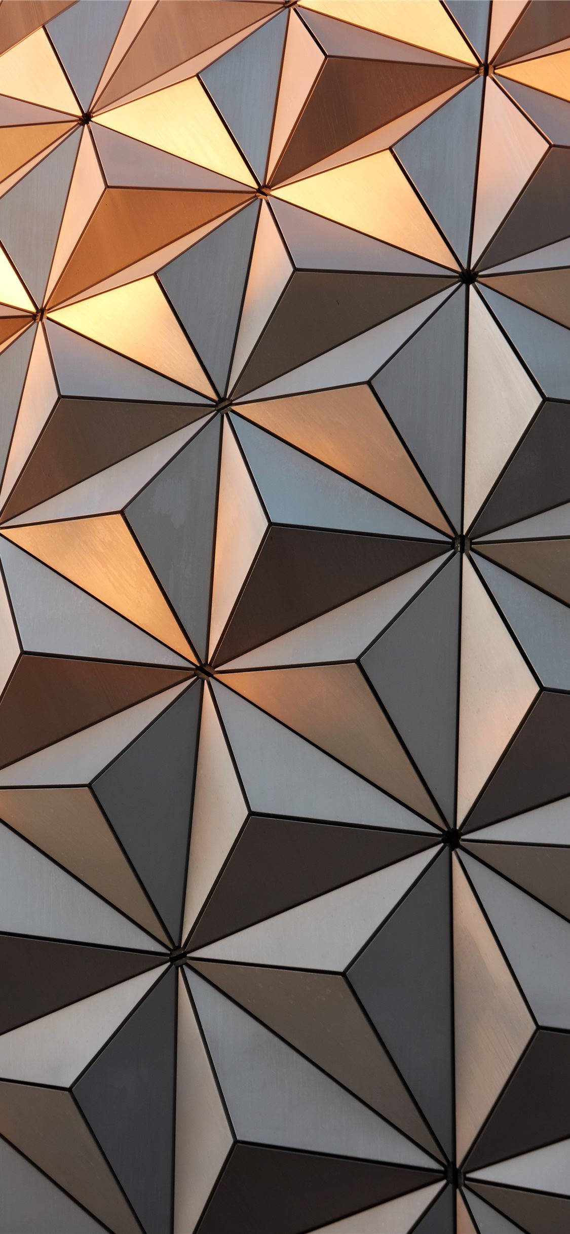 金色陽光下的Epcot地球儀 壁紙 — 幾何牆壁的近距離特寫，呈現溫暖金色與冷灰色調的三角形切面，捕捉柔和光線。