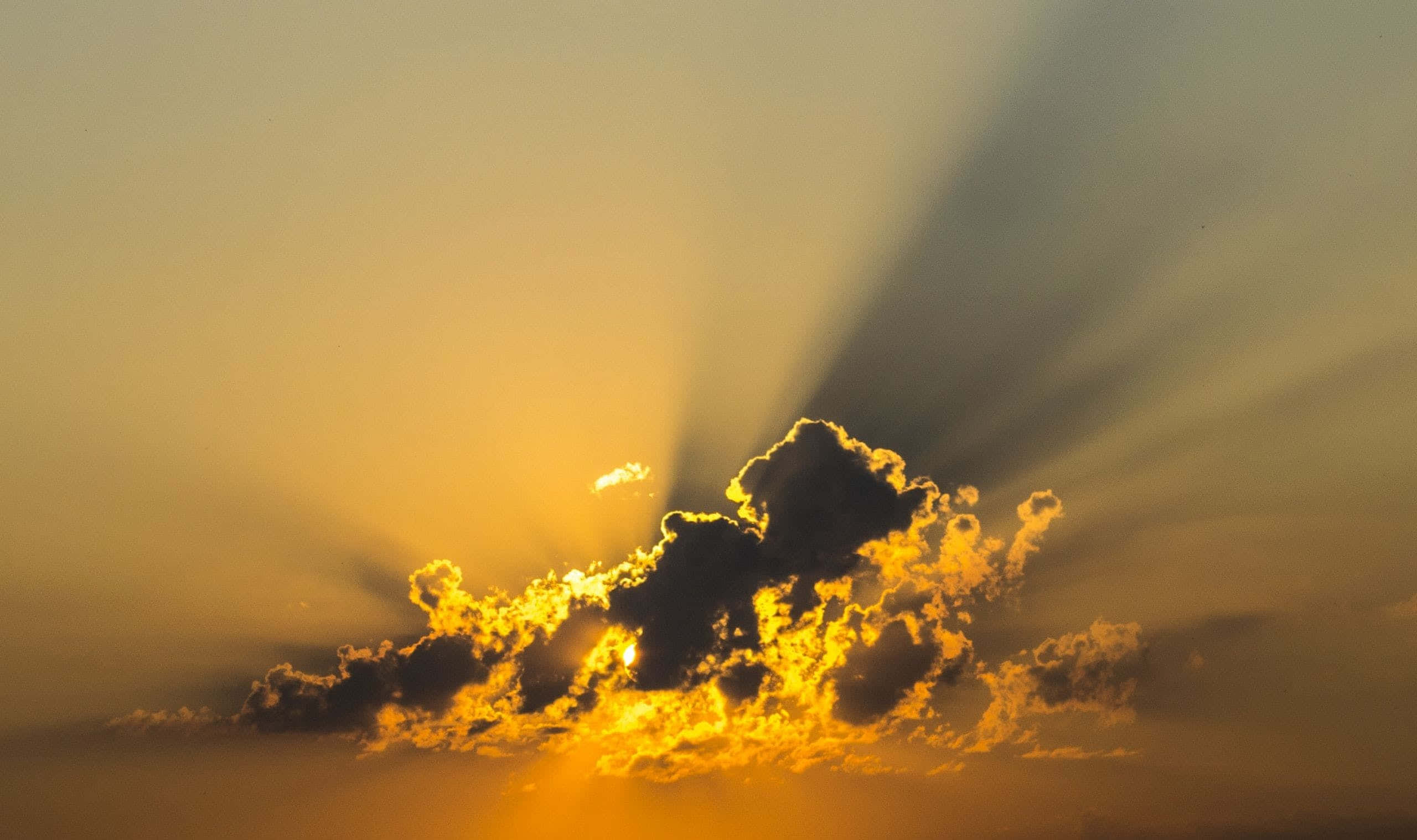 Yellow Sky 桌布 壁紙 — 金色陽光穿透戲劇性的雲層，在充滿活力的日落天空中。