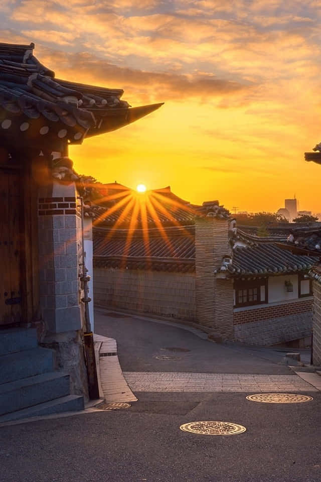 South Korea 桌布 壁紙 — 金色陽光穿過傳統瓦片屋頂，在日落時分將溫暖的光線投射在寧靜的歷史小巷中。