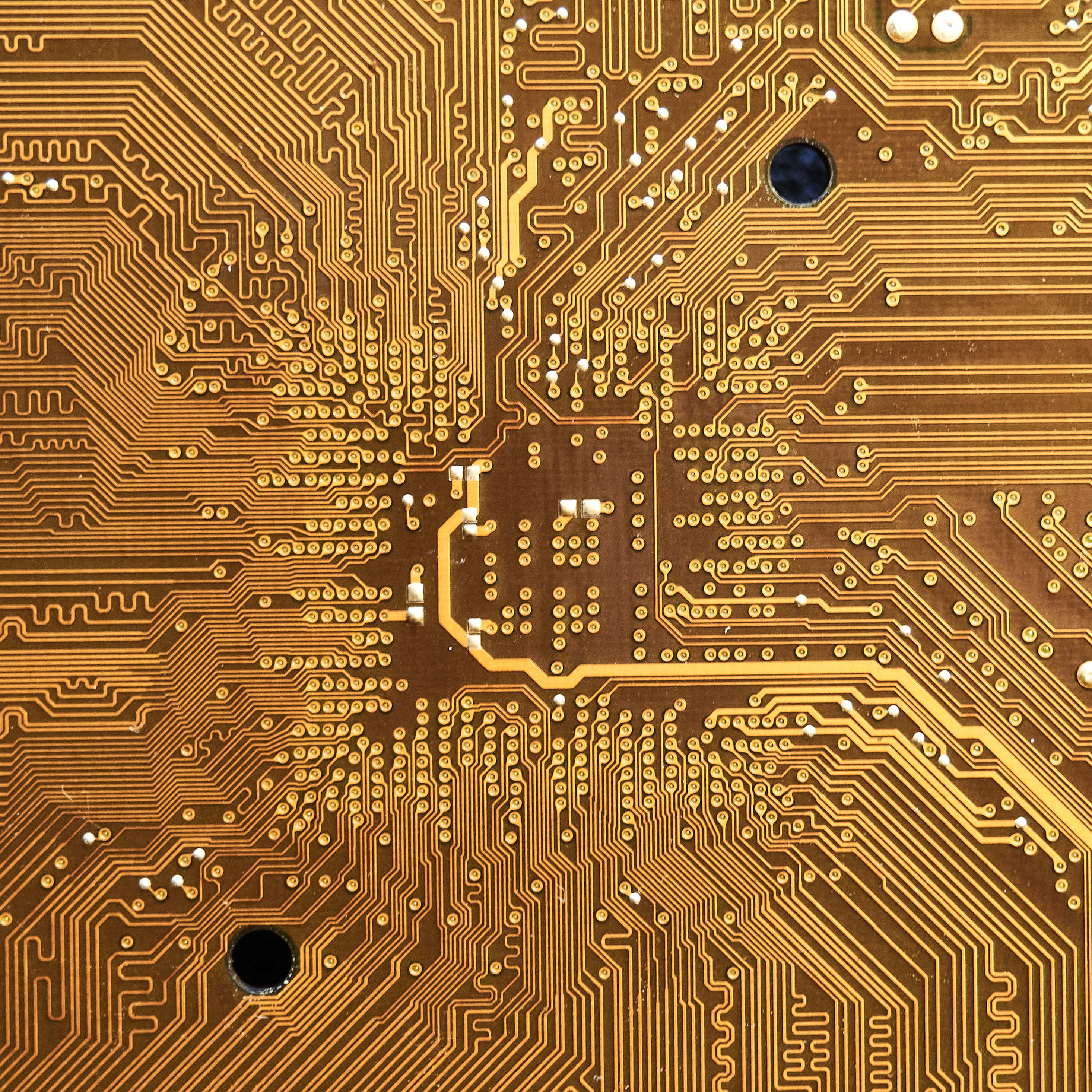 Circuit 桌布 壁紙 — 金色電路板的特寫，在棕色基板上帶有複雜的線路和焊點。