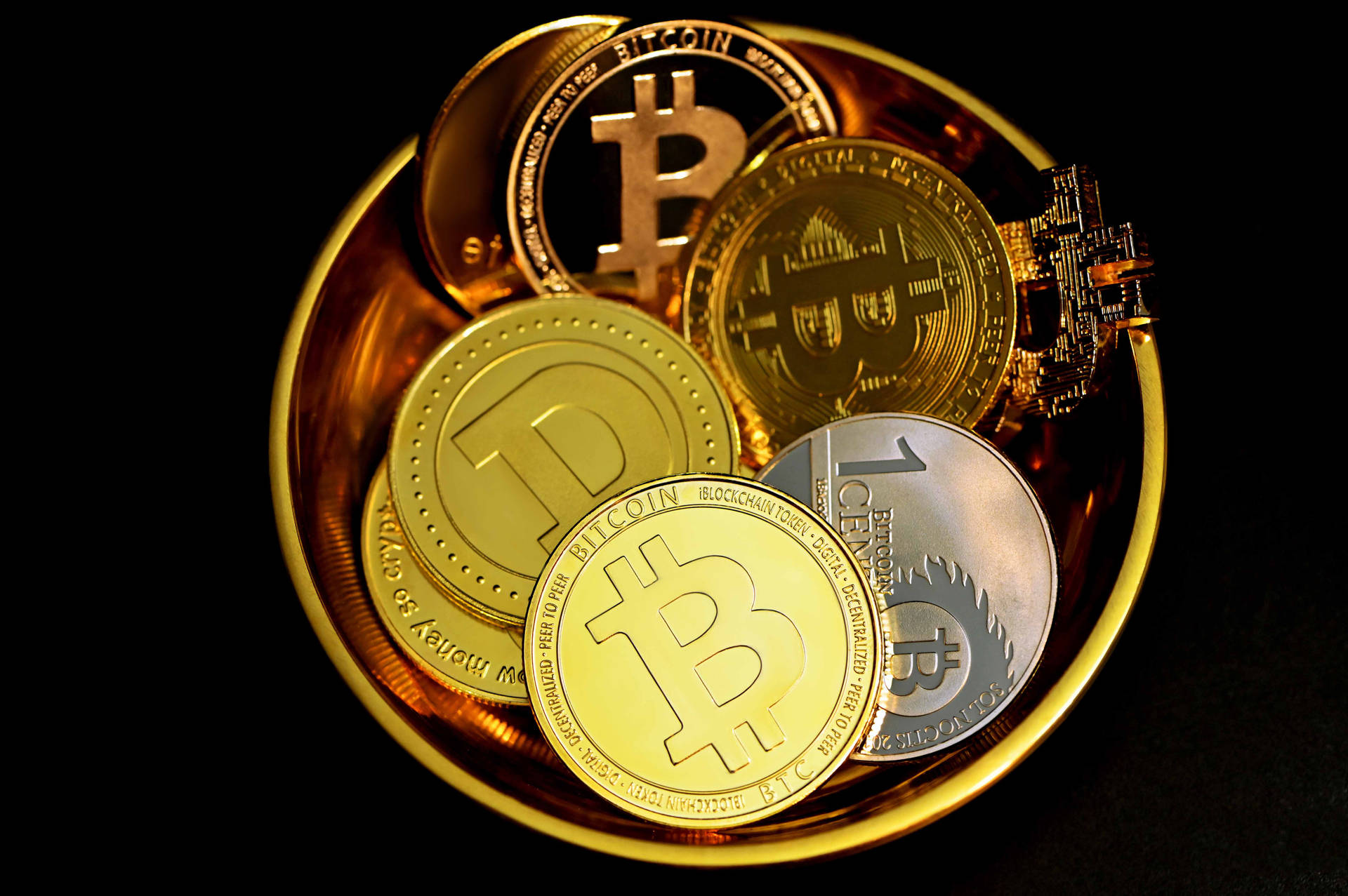 黑色背景的碗中的金色和銀色比特幣硬幣。