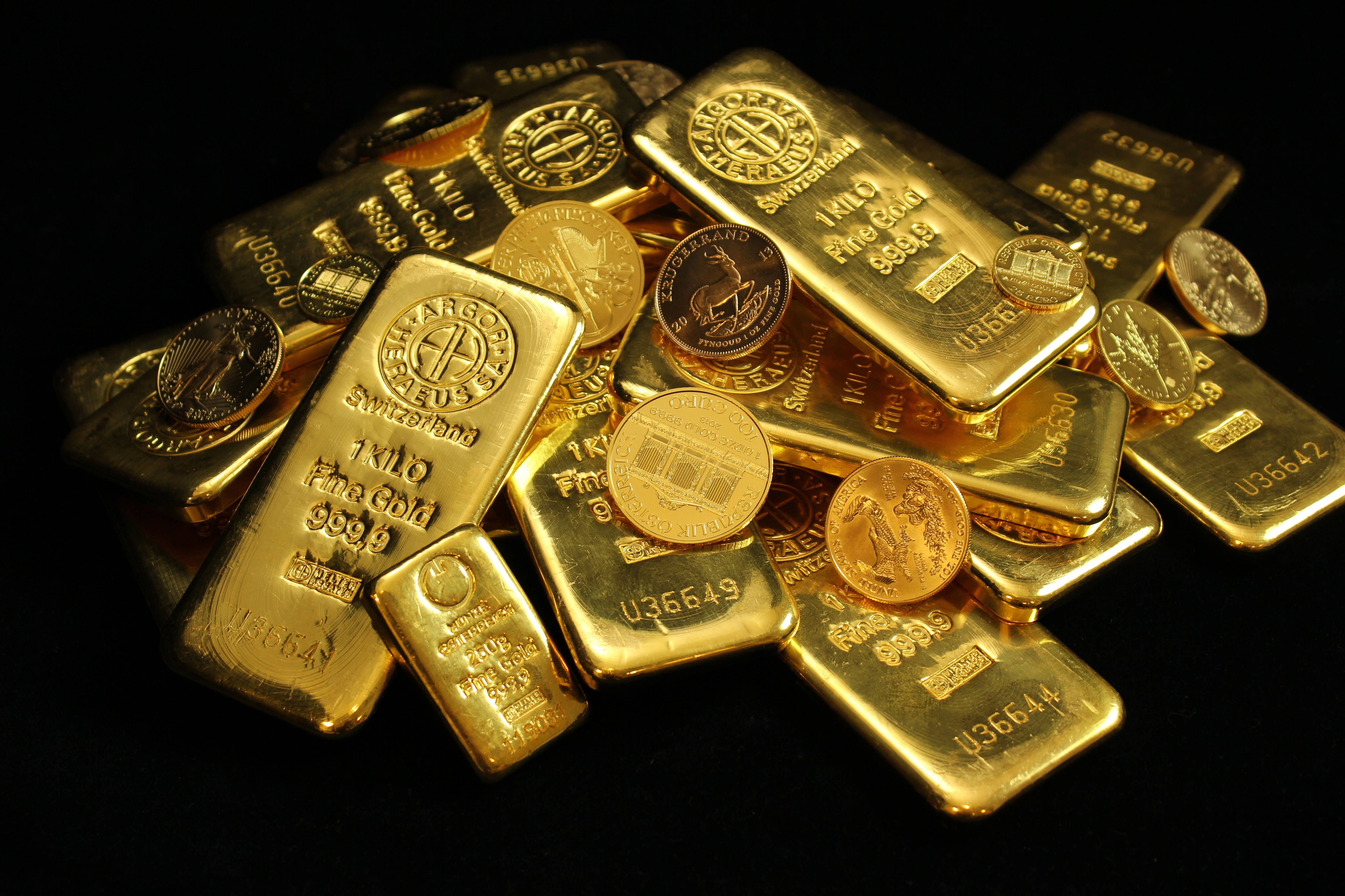金錢背景：金幣與金條 壁紙 — 閃閃發光的金條和金幣堆疊在黑色背景上，反射光線。