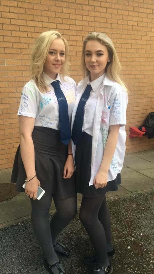 兩個穿著校服的十幾歲女孩站在磚砌建築外。