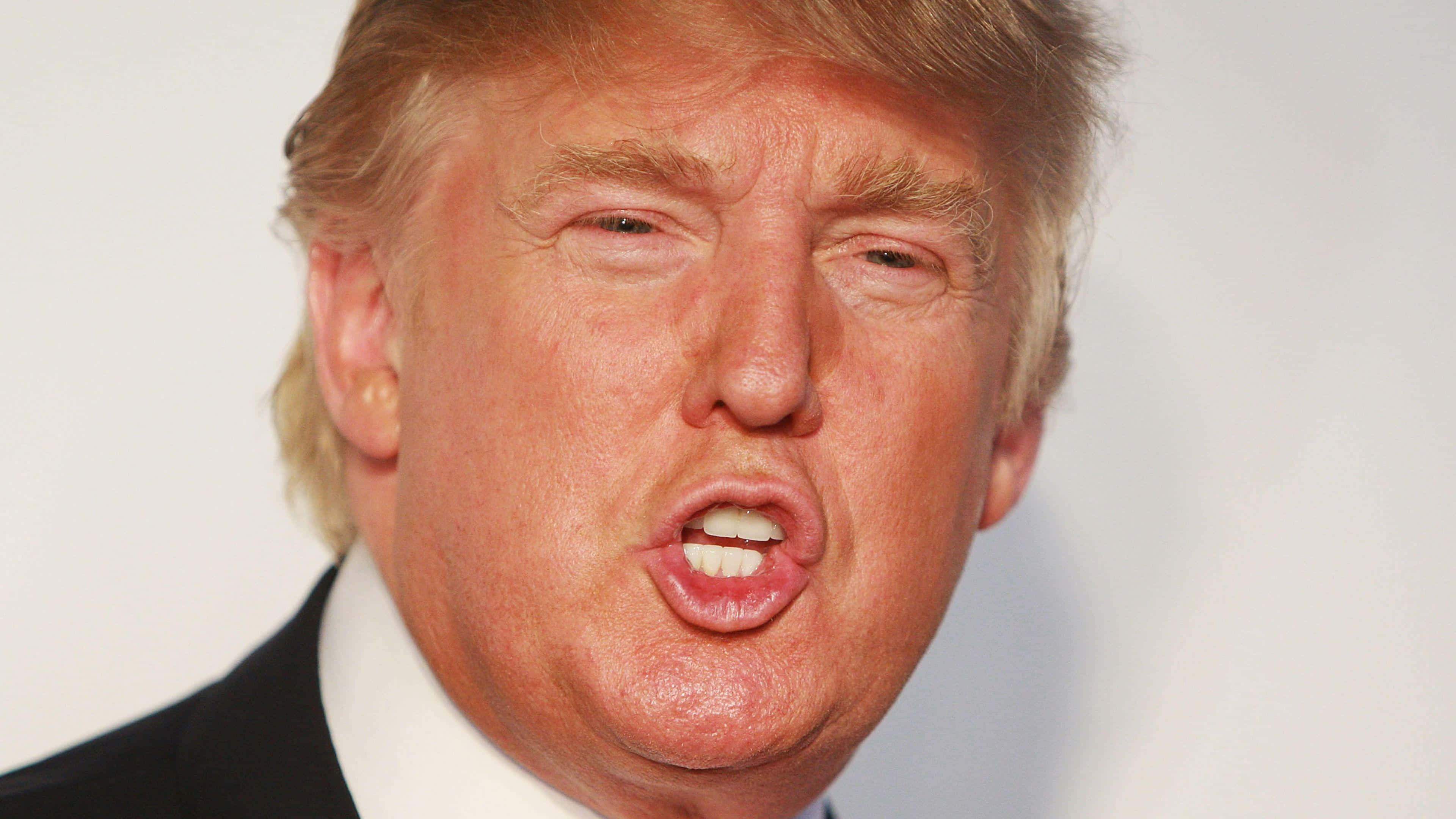 trump 桌布 壁紙 — 金髮男子身穿西裝，在純白背景前做出表情豐富的面部特寫。
