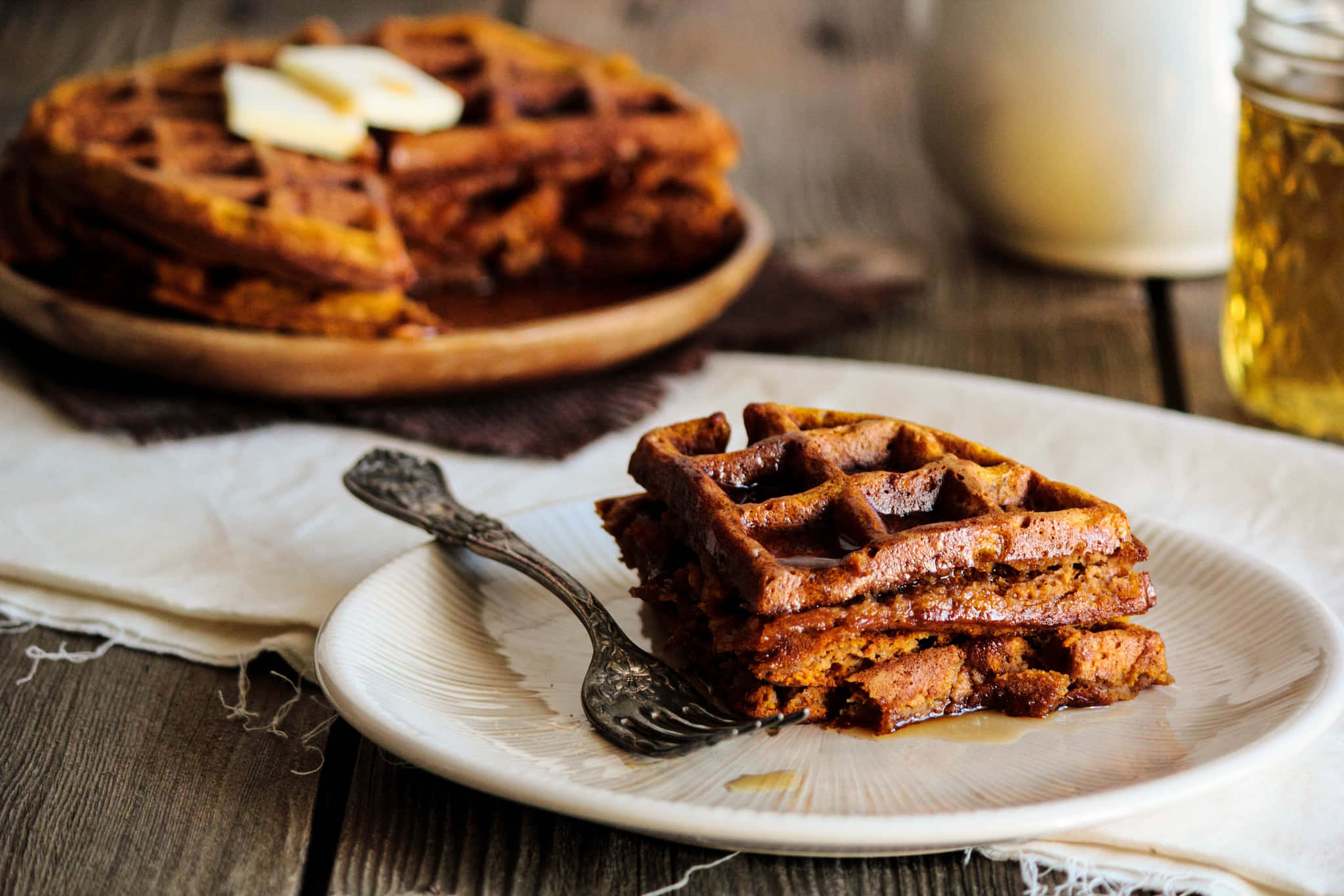 Waffle 桌布 壁紙 — 金黃色的南瓜窩夫疊放在碟上，配上牛油和糖漿，置於鄉村風木桌上。