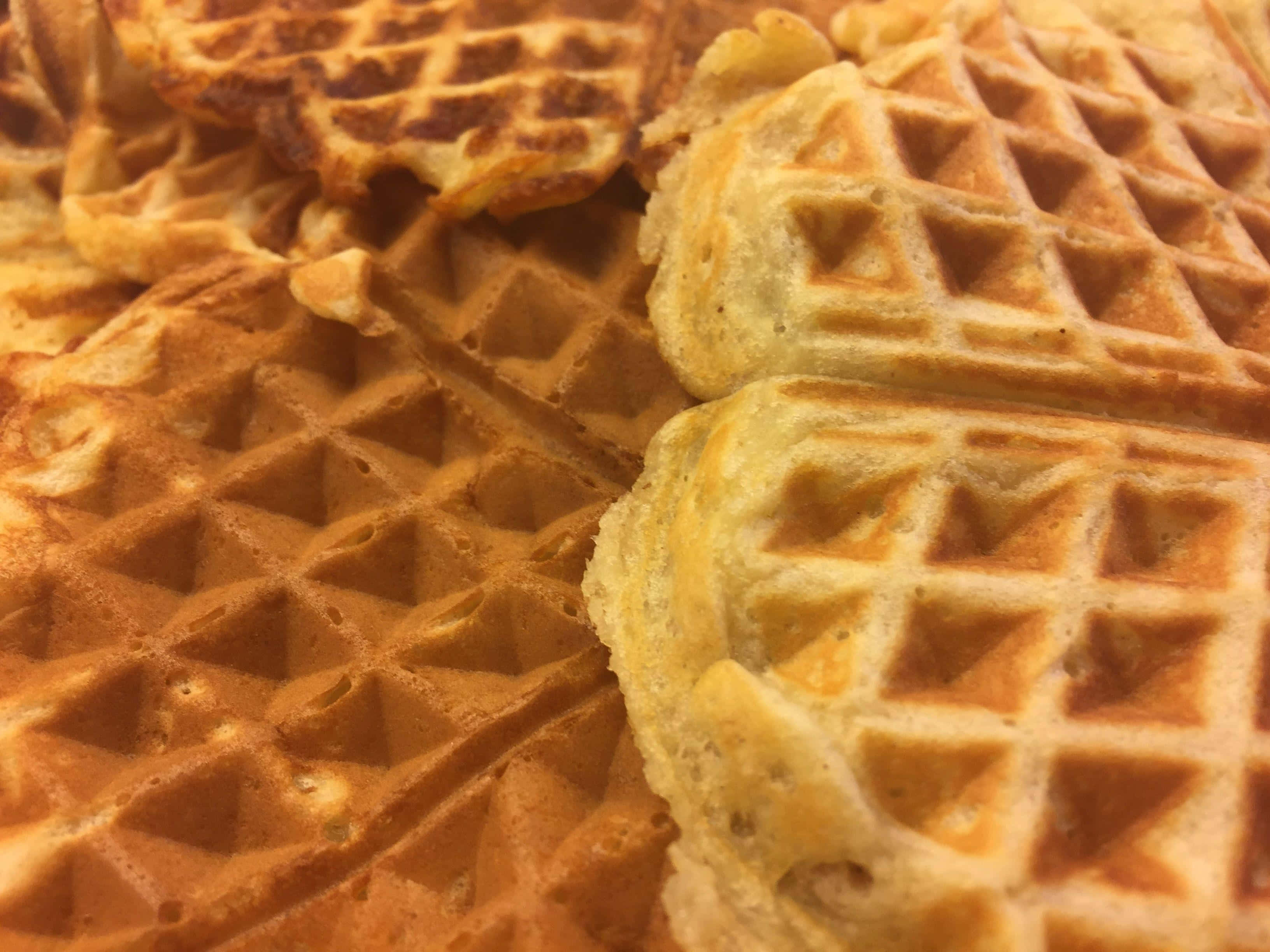 Waffle 桌布 壁紙 — 金黃色的窩夫，邊緣酥脆，中心柔軟，堆疊成溫暖誘人的一堆。