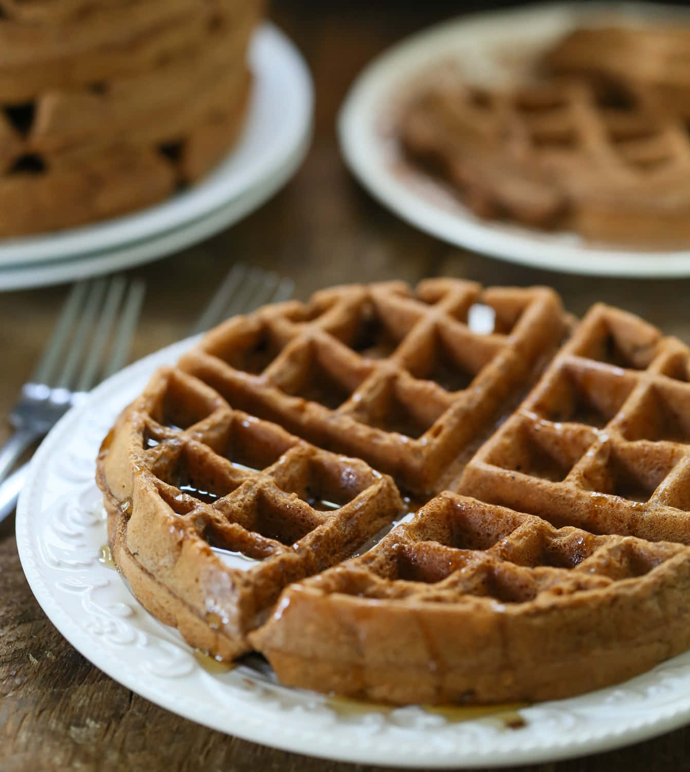 Waffle 桌布 壁紙 — 金黃色的窩夫在白色碟子上閃閃發光，放在質樸的木桌上。