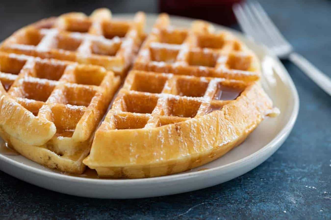 Waffle 桌布 壁紙 — 金黃色的窩夫撒上糖粉並淋上糖漿，誘人地放在白色碟子上。