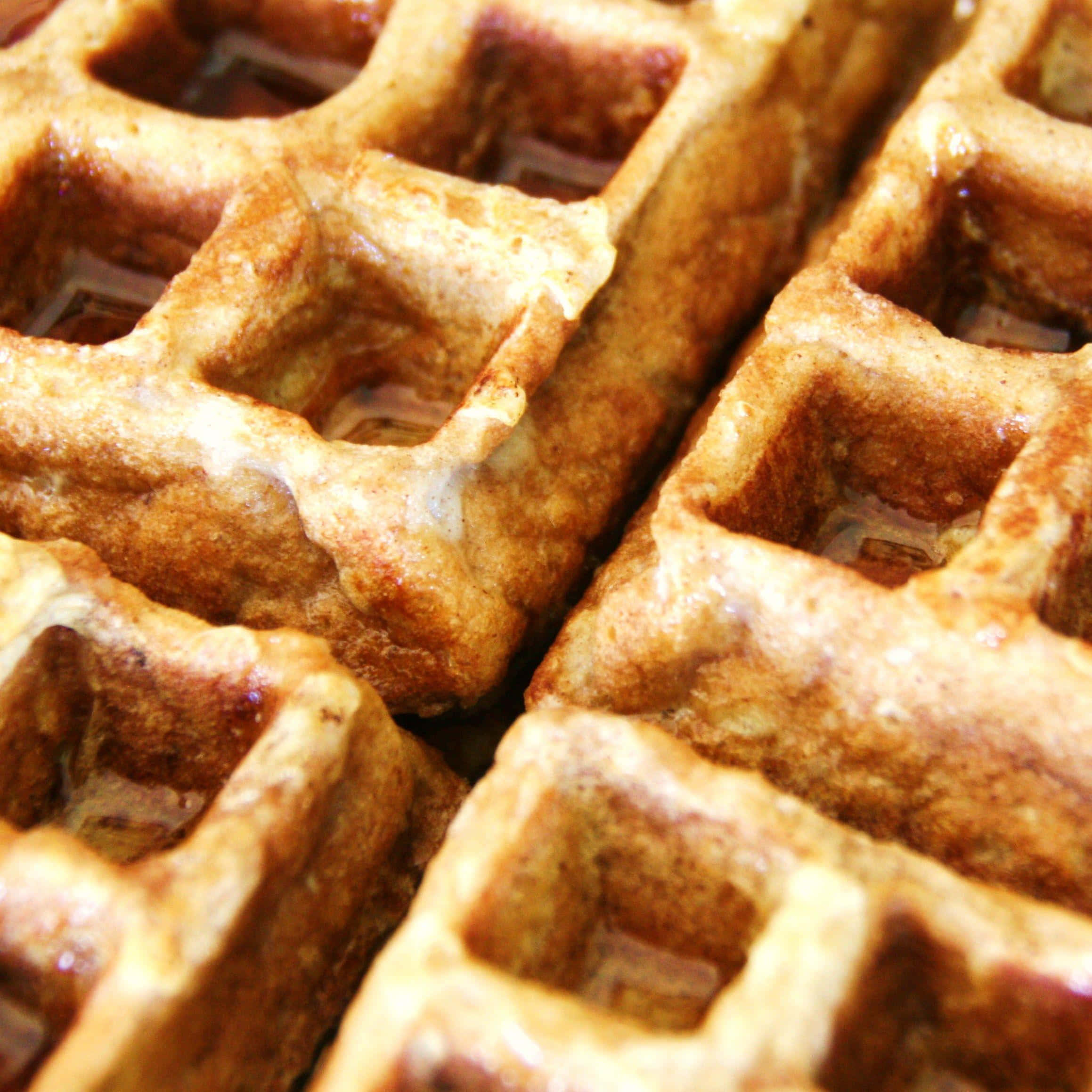 Waffle 桌布 壁紙 — 金黃色窩夫在特寫鏡頭中閃爍著糖漿，突顯其酥脆質感。